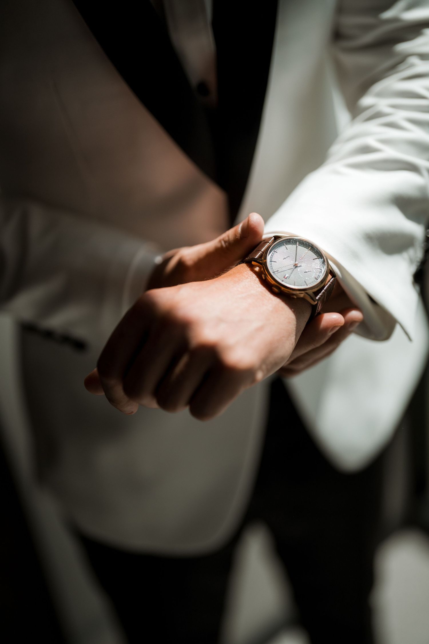 Close-up shots of hands checking an elegant wristwatch while wearing a white formal jacket.