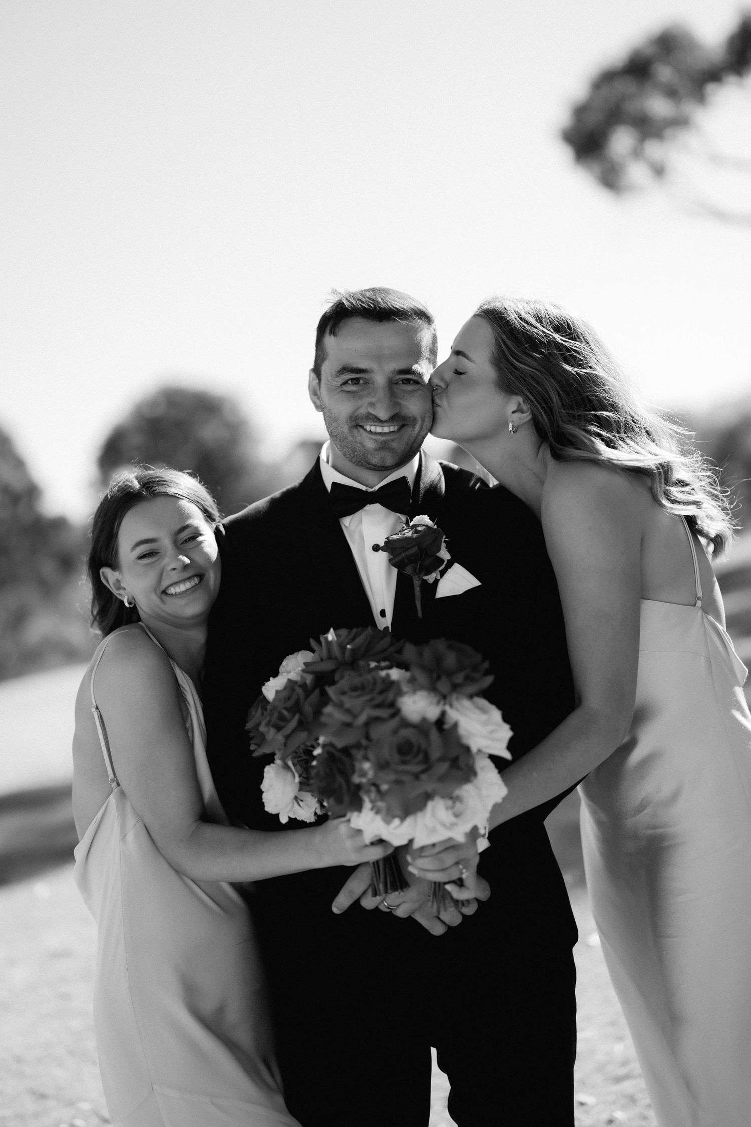Wedding party members share joyful moments together in black and white photography.