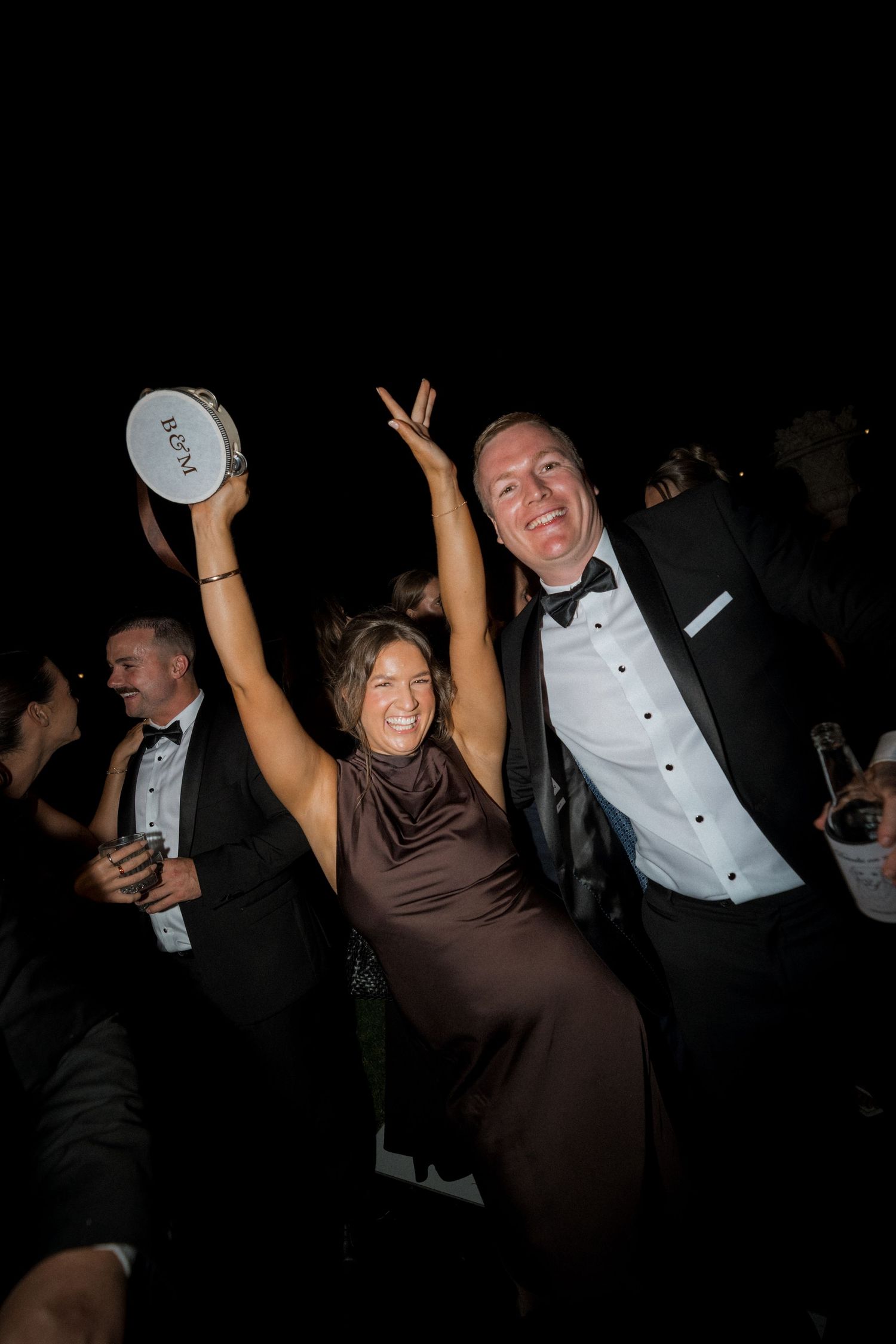 Wedding guests dancing and celebrating at night with joyful expressions.