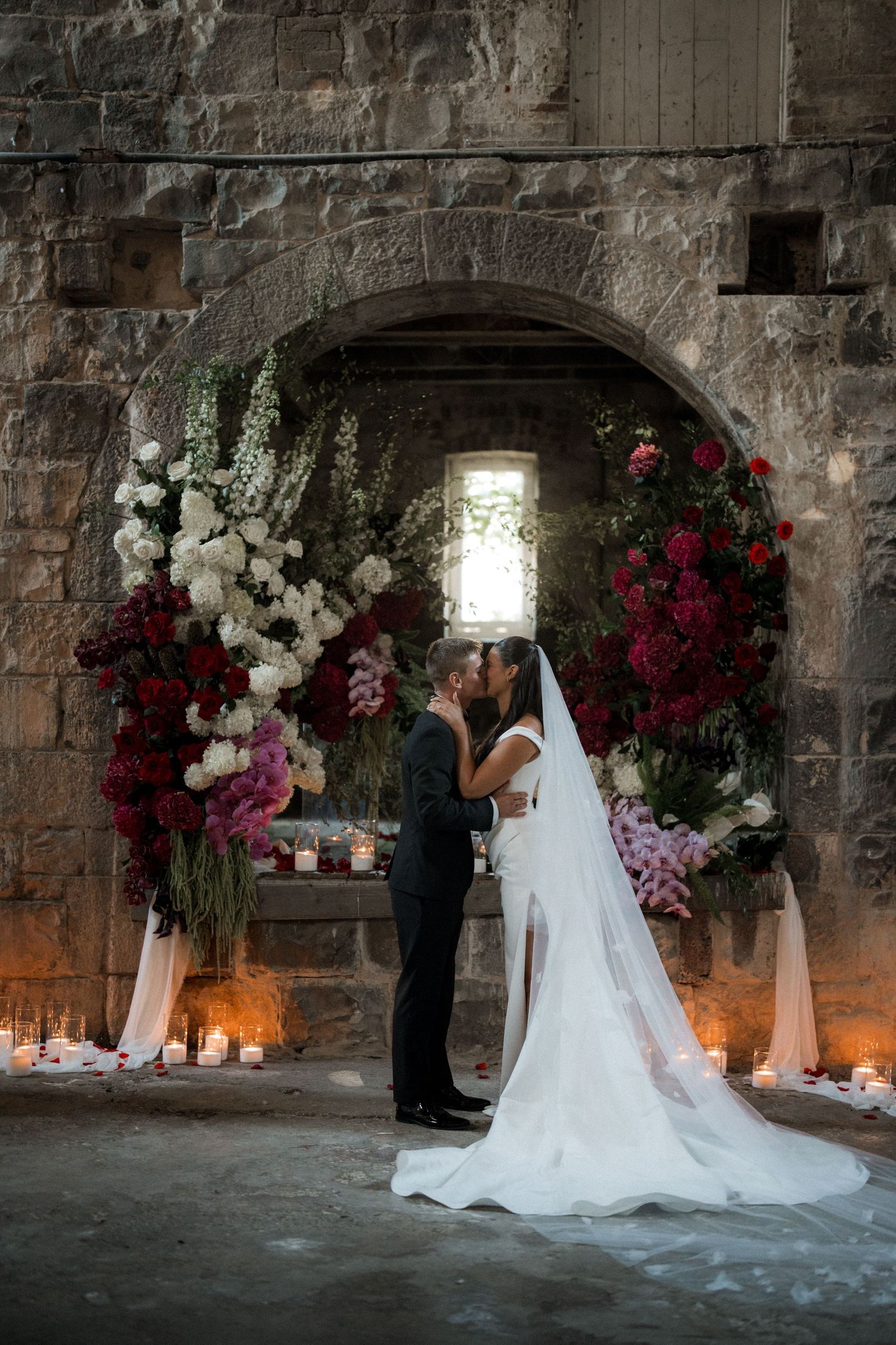 Elegant wedding ceremony setup in stone castle room with floral arrangements and candlelight.