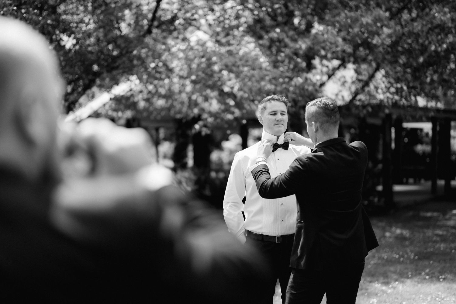 Black and white images show a stylish outdoor wedding celebration with elegant formal attire and natural surroundings.