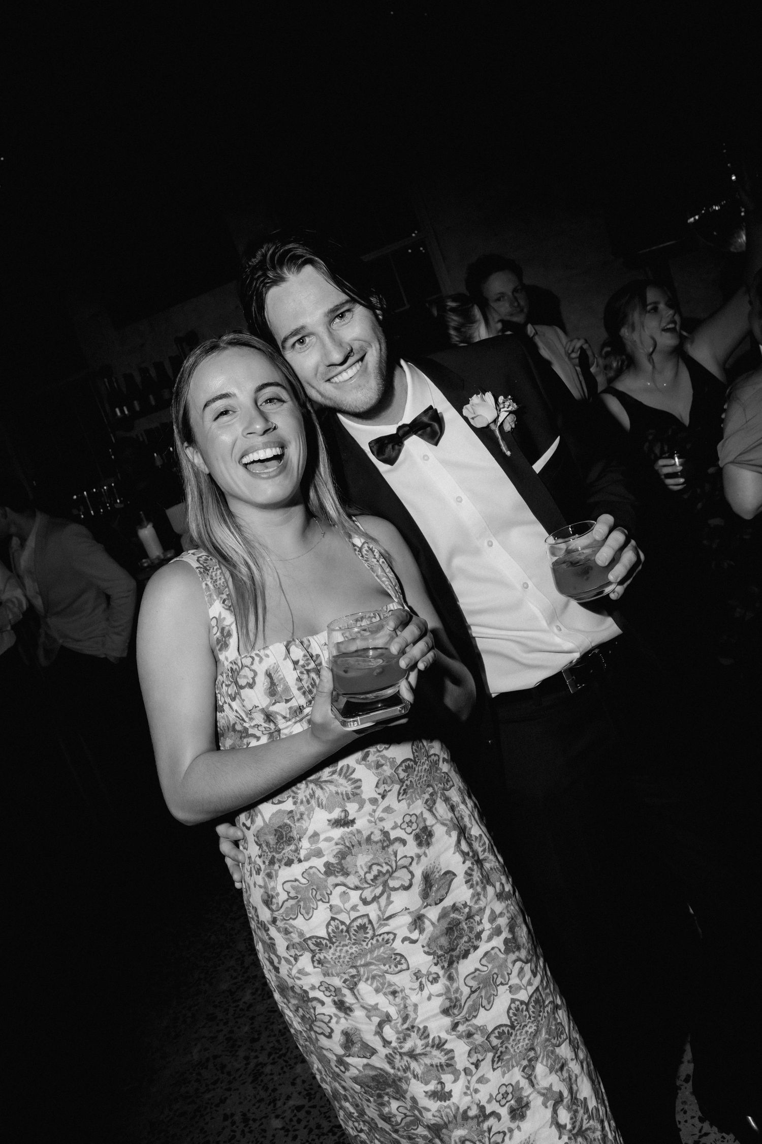 Black and white candid shot of party guests enjoying themselves at a reception.