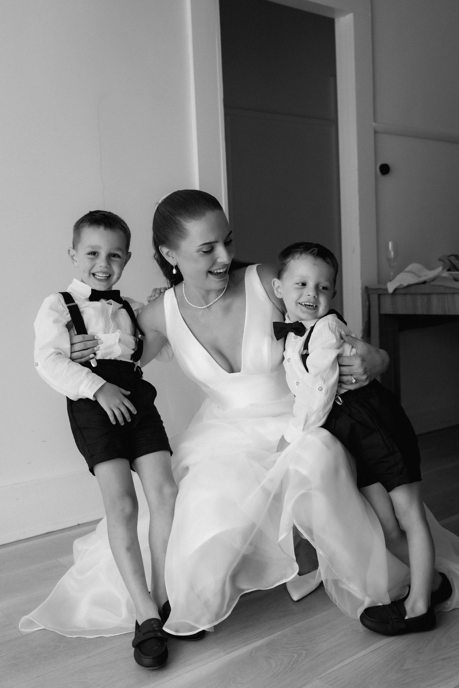 Black and white photo of a joyful moment with two young boys in formal attire.