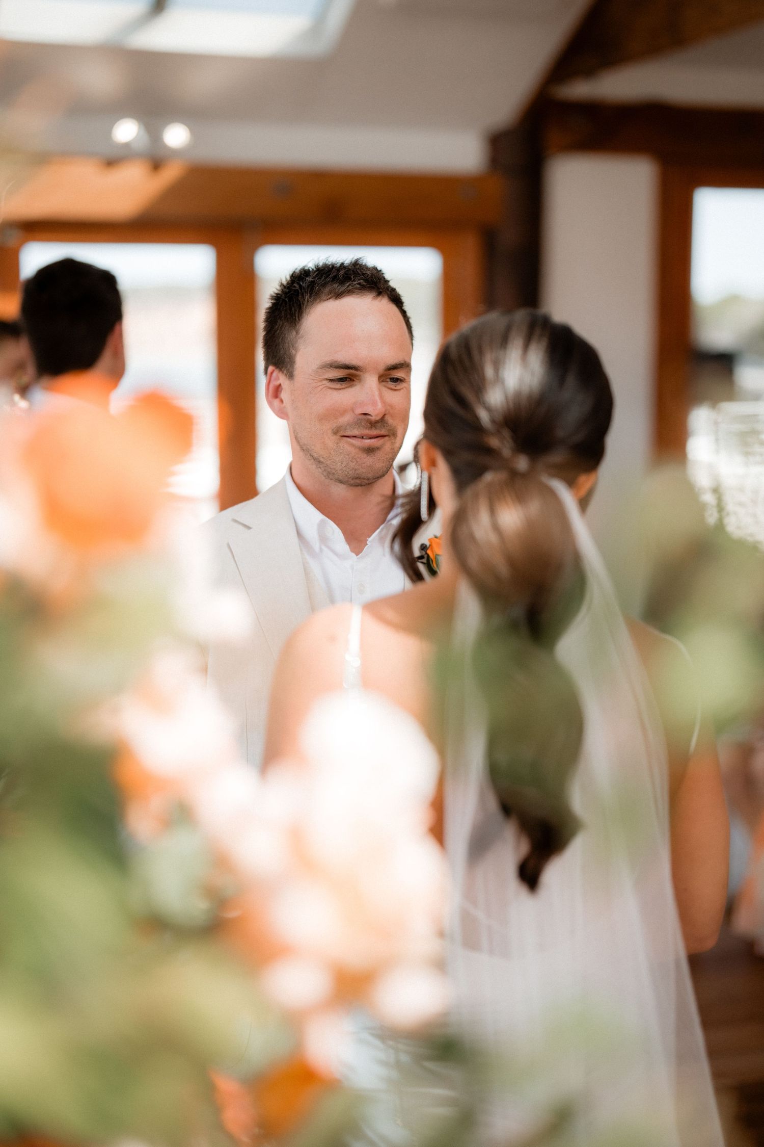 Wedding celebration in a bright indoor venue with wooden floors and large windows.