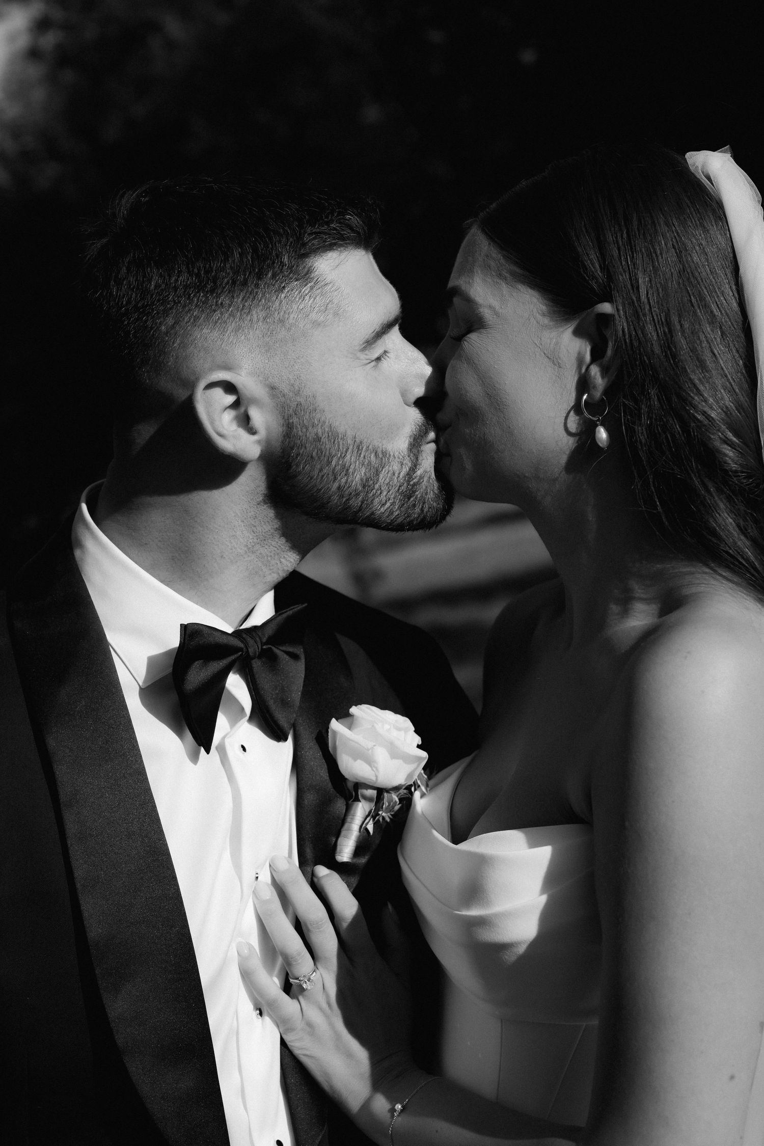 An intimate black and white portrait captures a romantic moment in formal attire.