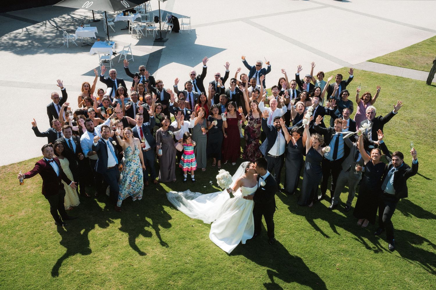 Wedding party members jump in celebration on a sunny lawn creating dynamic silhouettes in sequence.