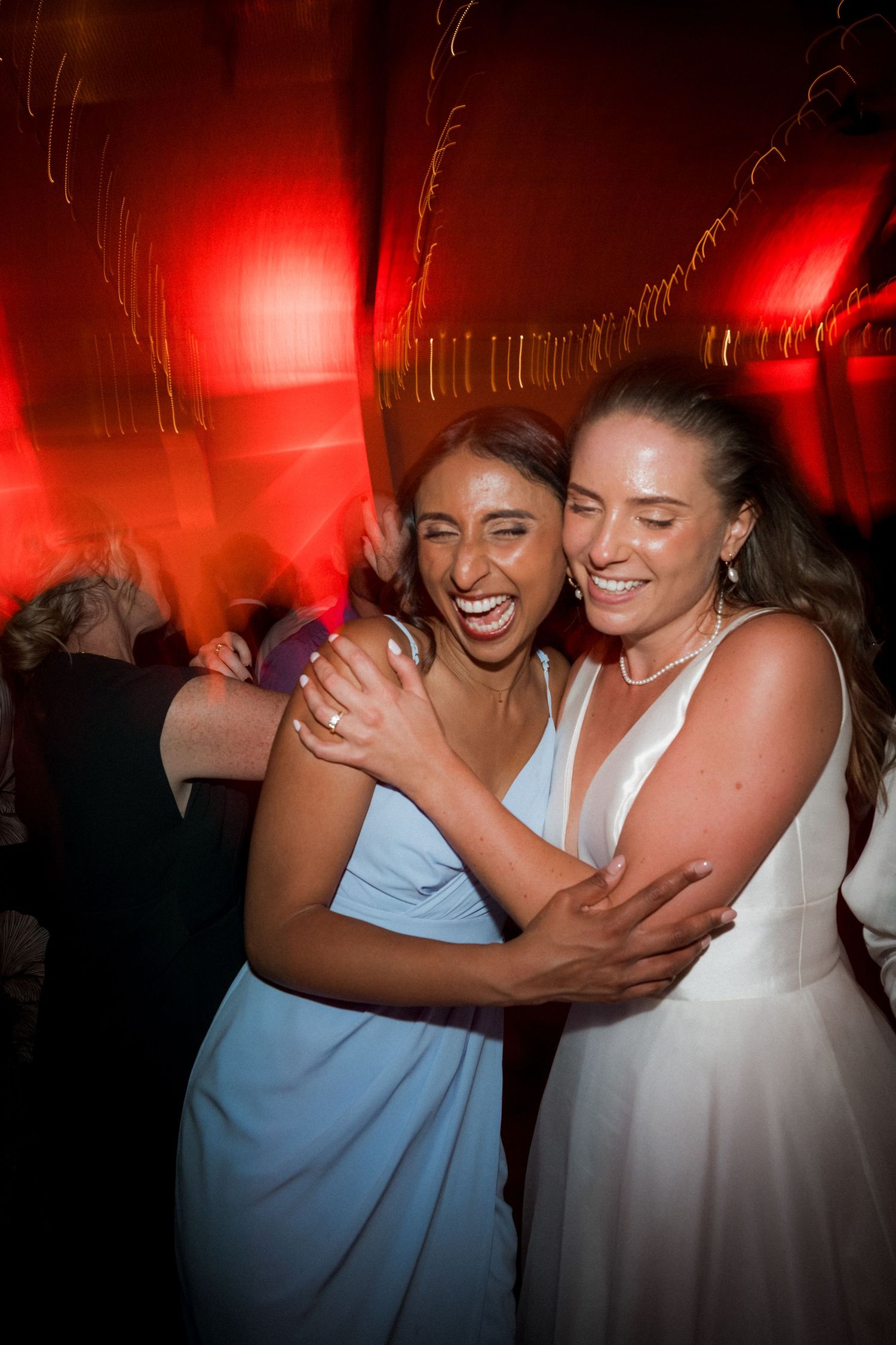 Wedding reception dance floor scene illuminated with vibrant red lighting creating a festive atmosphere.