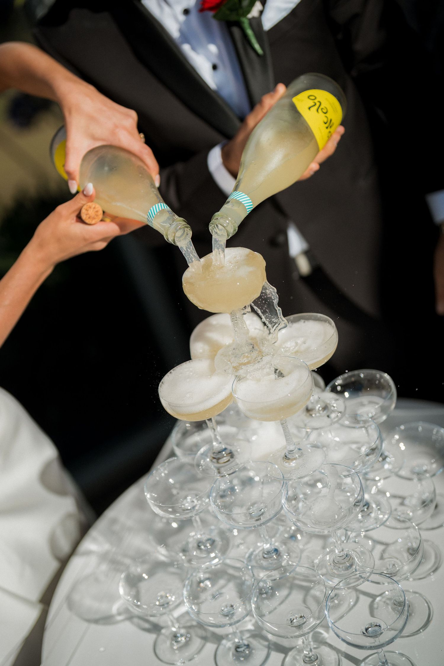 Champagne being poured into a tower of stacked crystal glasses for a wedding celebration.