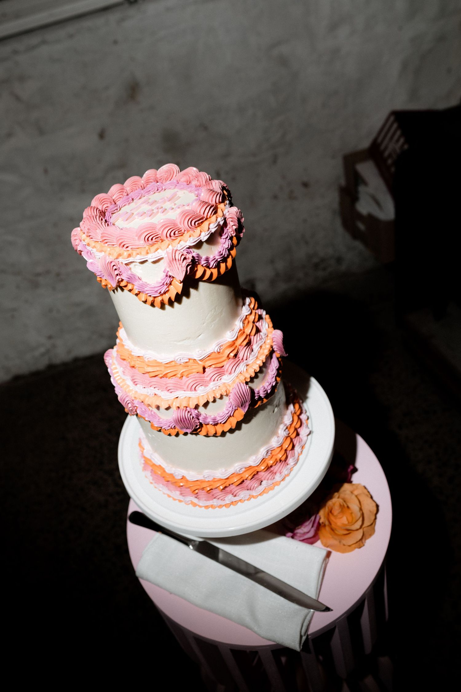 Three-tiered wedding cake with pink frosting details and delicate piping work.
