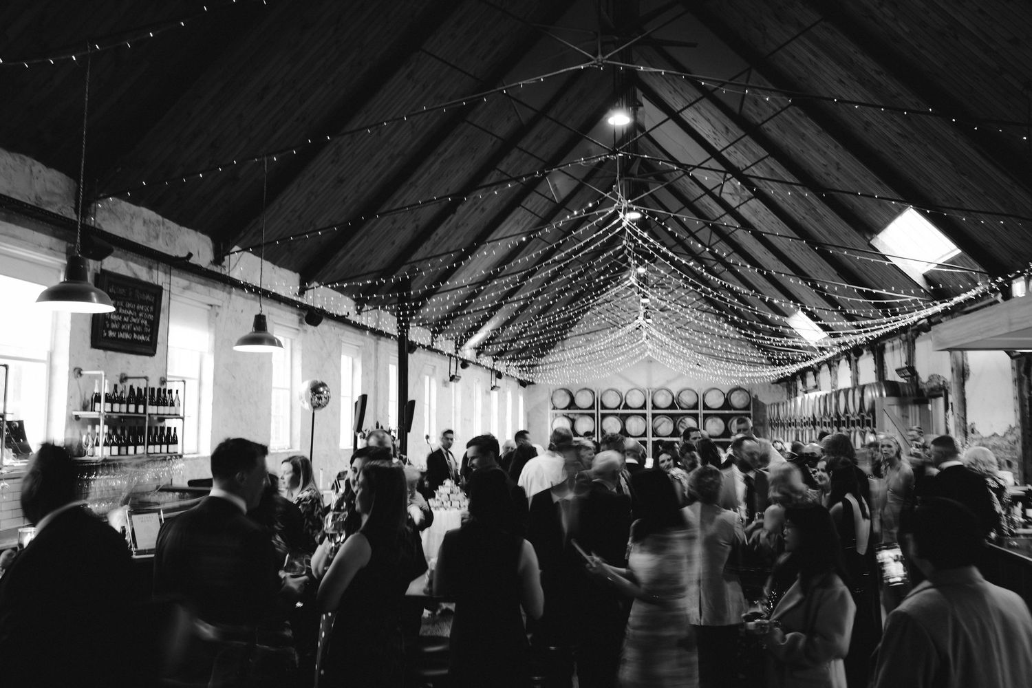 A series of black and white photos showing a large tent venue with string lights and guests during an evening event.