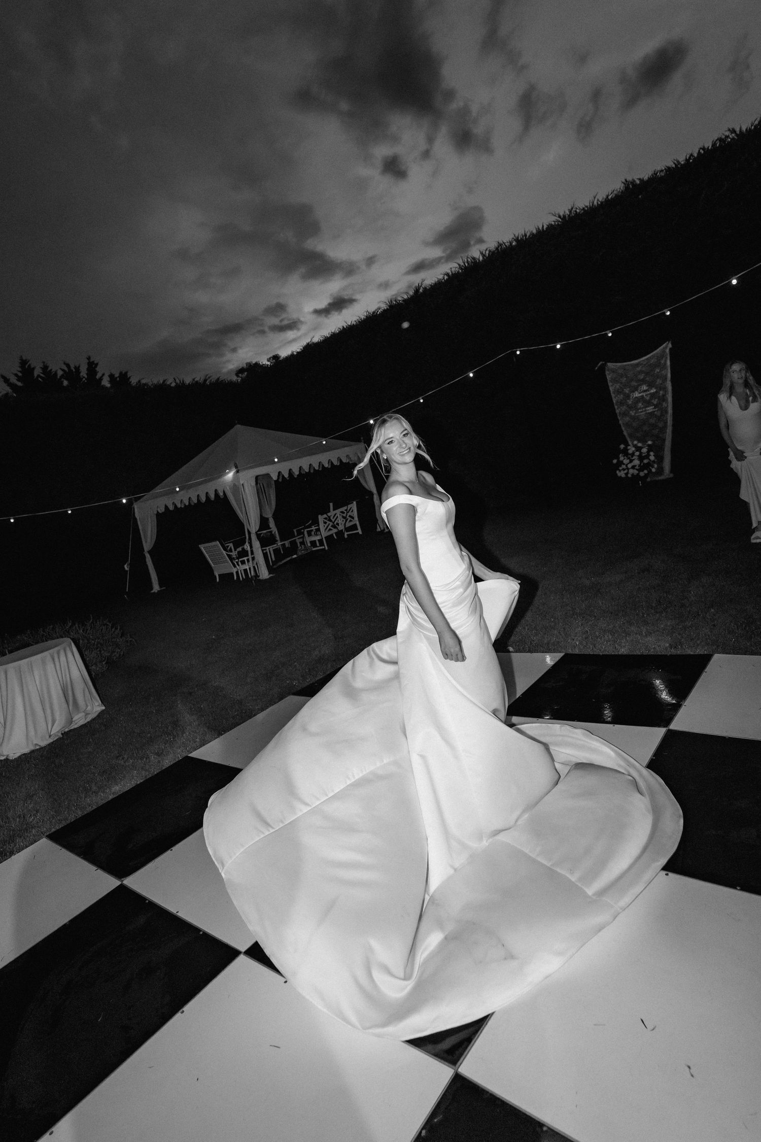 Black and white dance floor with string lights overhead at outdoor wedding reception.