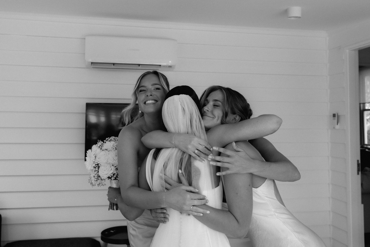 Black and white photo showing emotional embraces during wedding preparations.