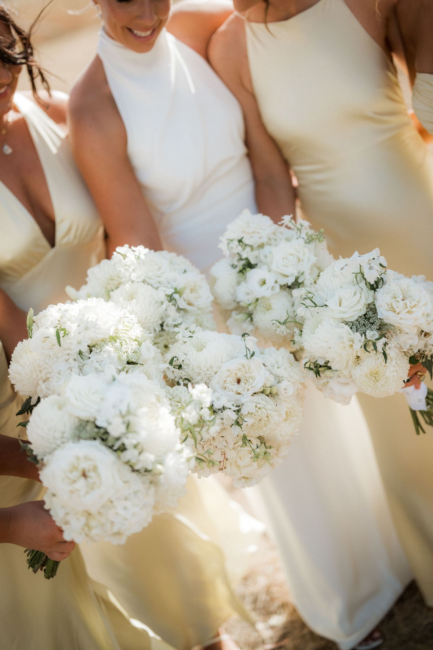 Row of elegant white bouquets held by wedding party members in matching dresses.