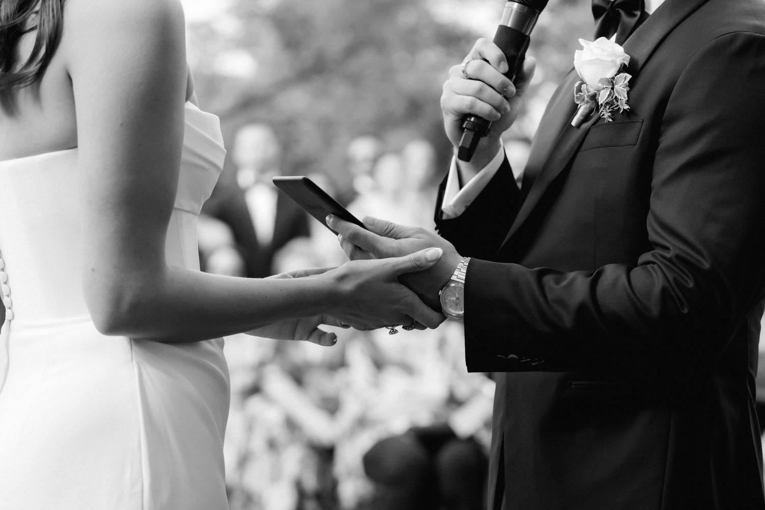 Wedding ceremony participants exchange rings during an intimate outdoor celebration.
