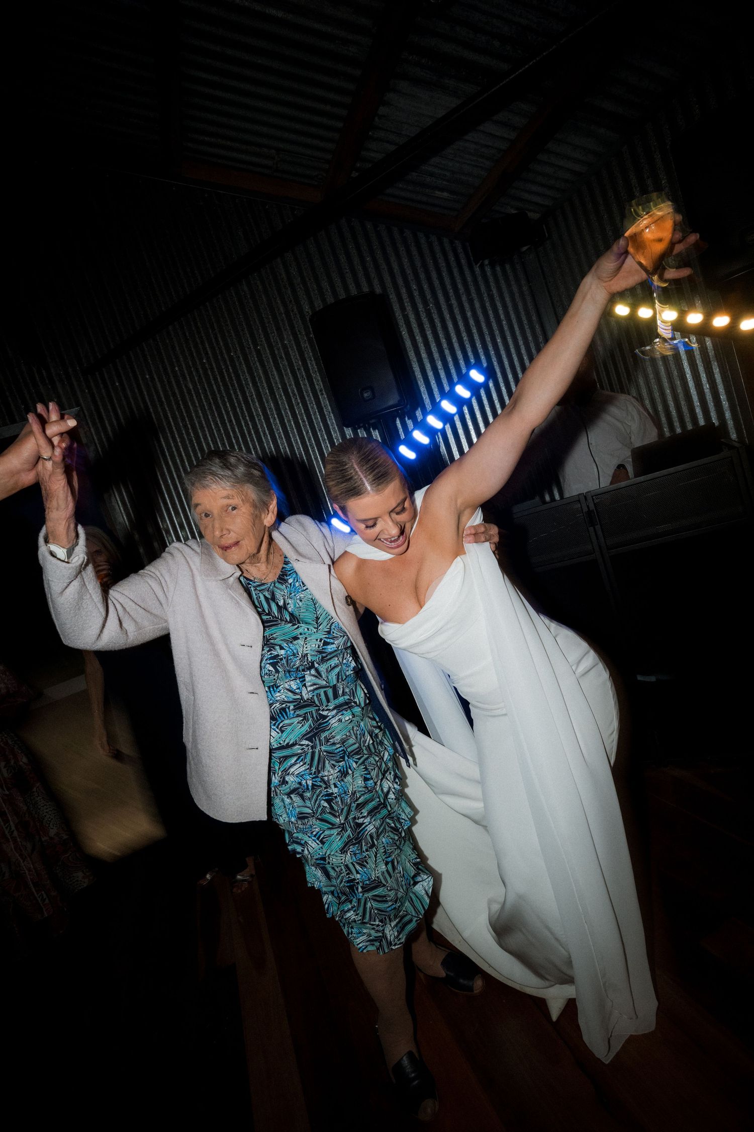 Wedding guests dancing and celebrating at a dimly lit reception venue.