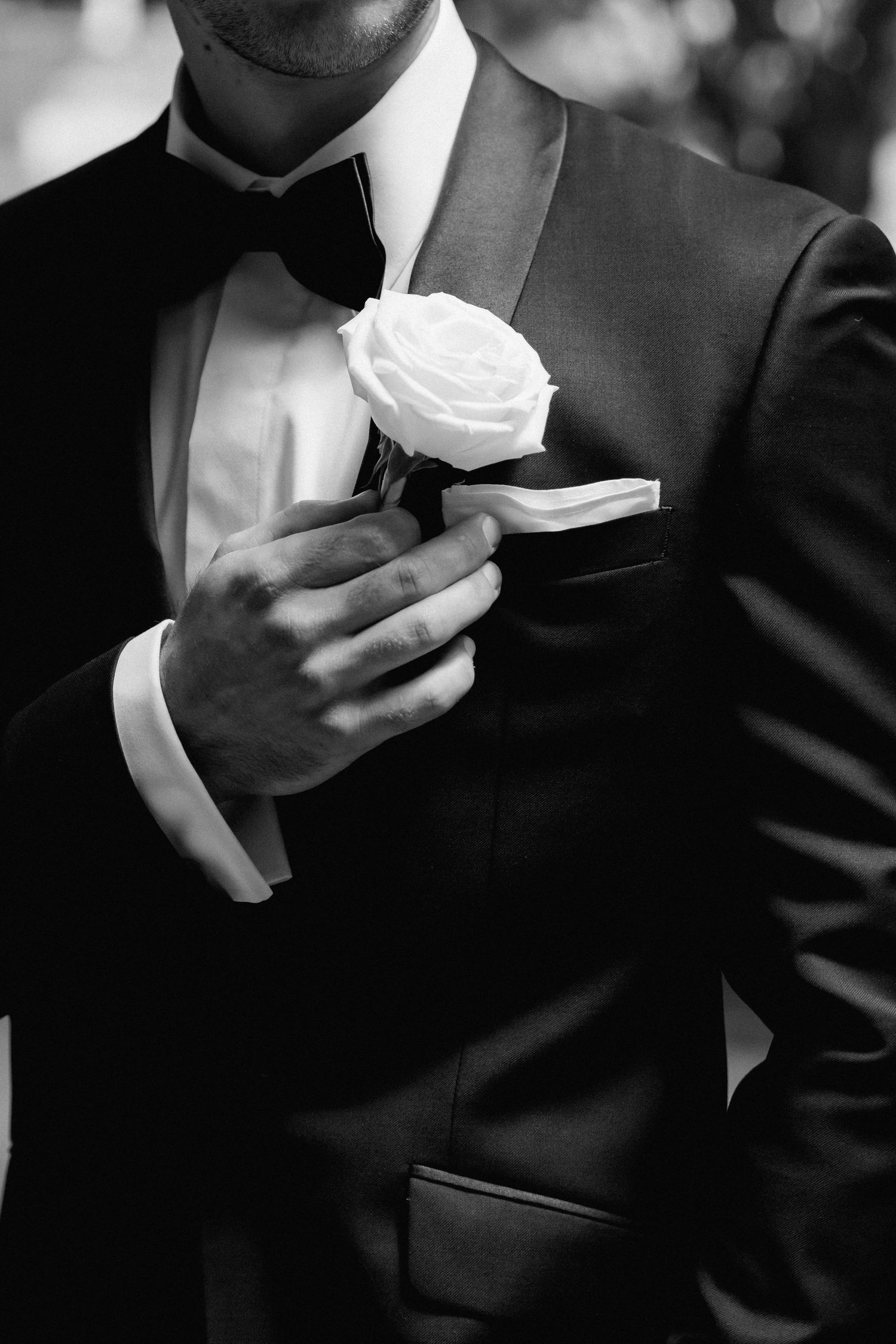 Groomsmen in black suits hold white roses in a sequence of candid moments.