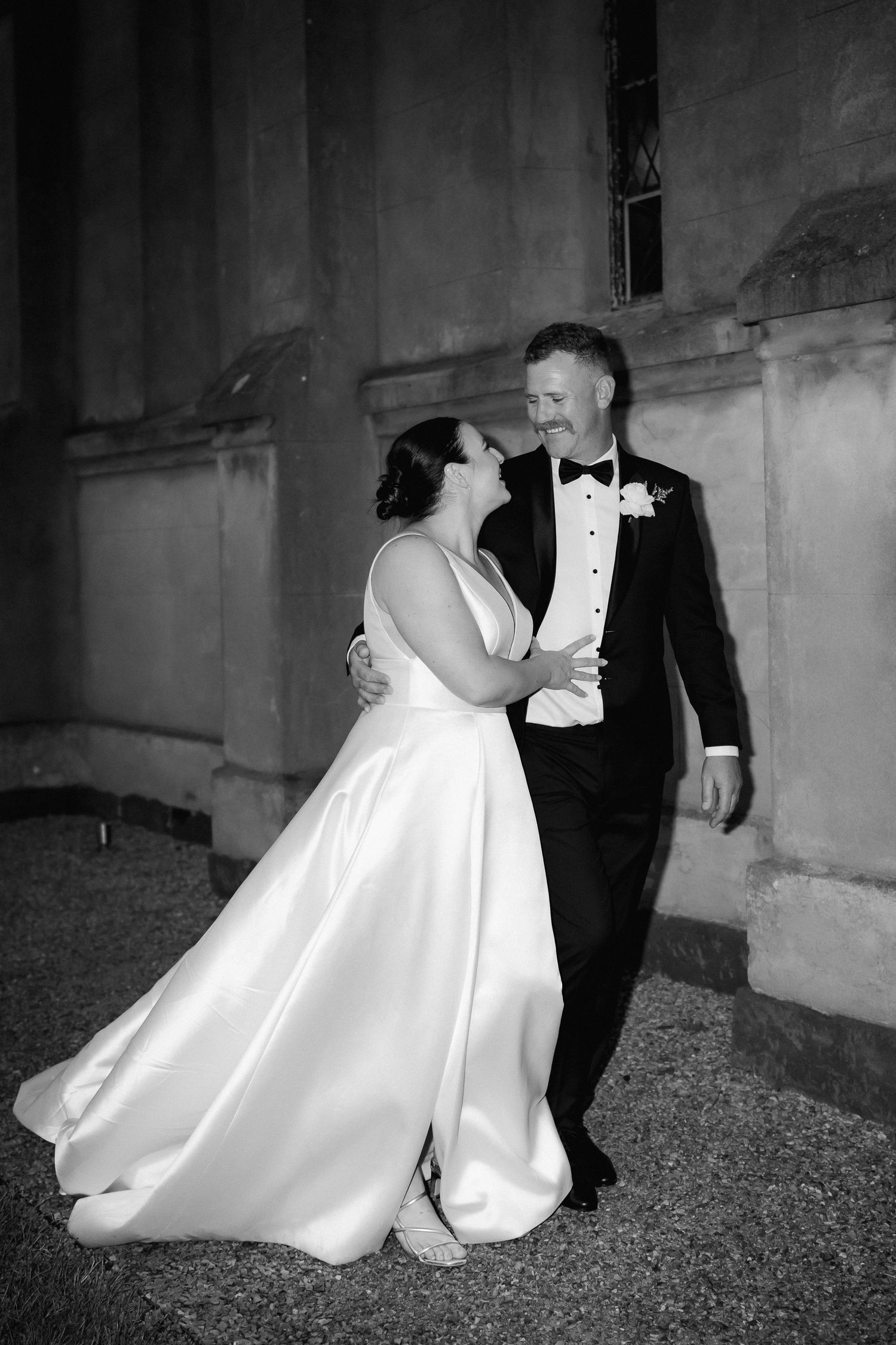 Black and white photo of newlyweds dancing together at their wedding, with the bride in a flowing white gown.