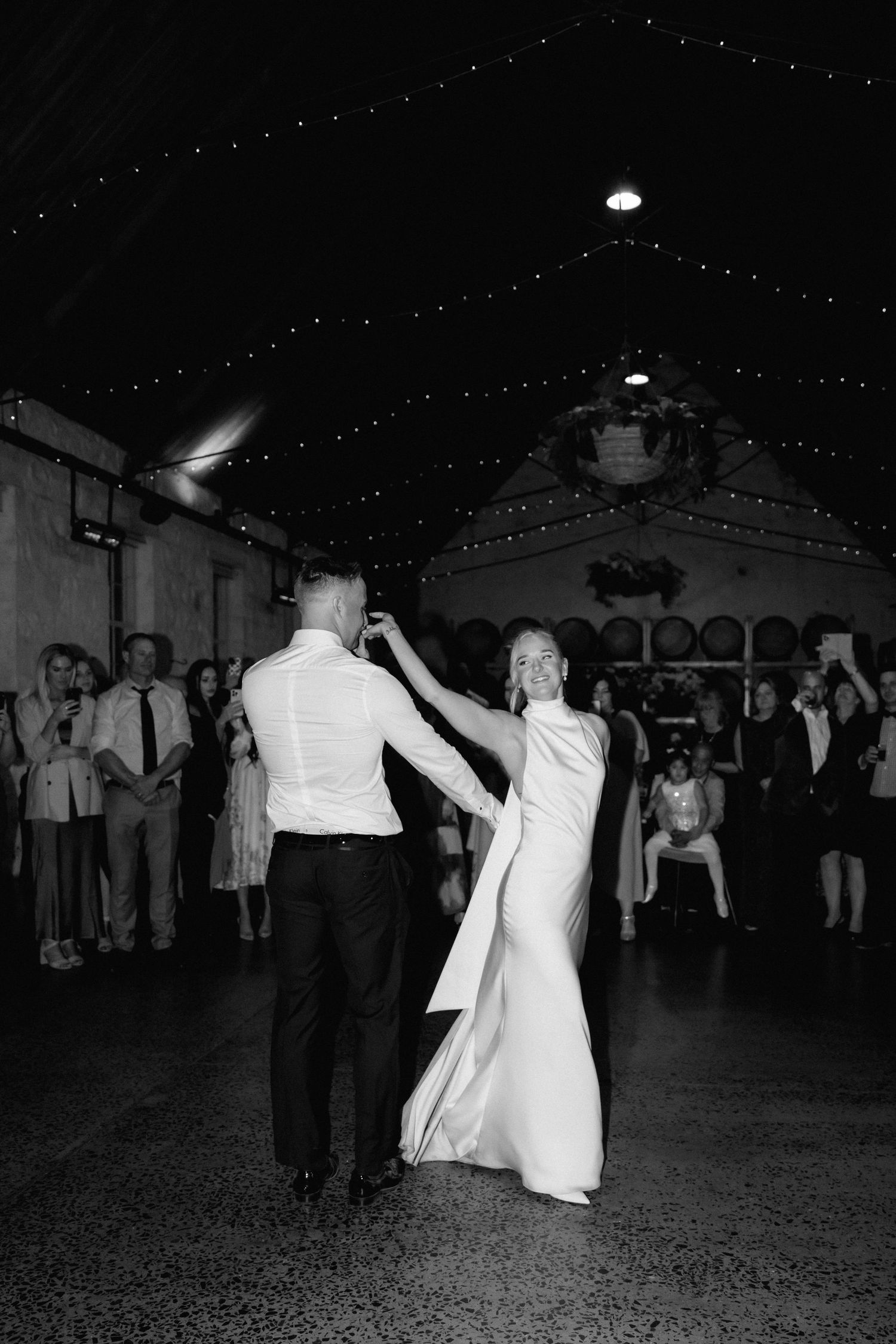 Group of wedding guests dancing on a low-lit dance floor in black and white captured across multiple frames.