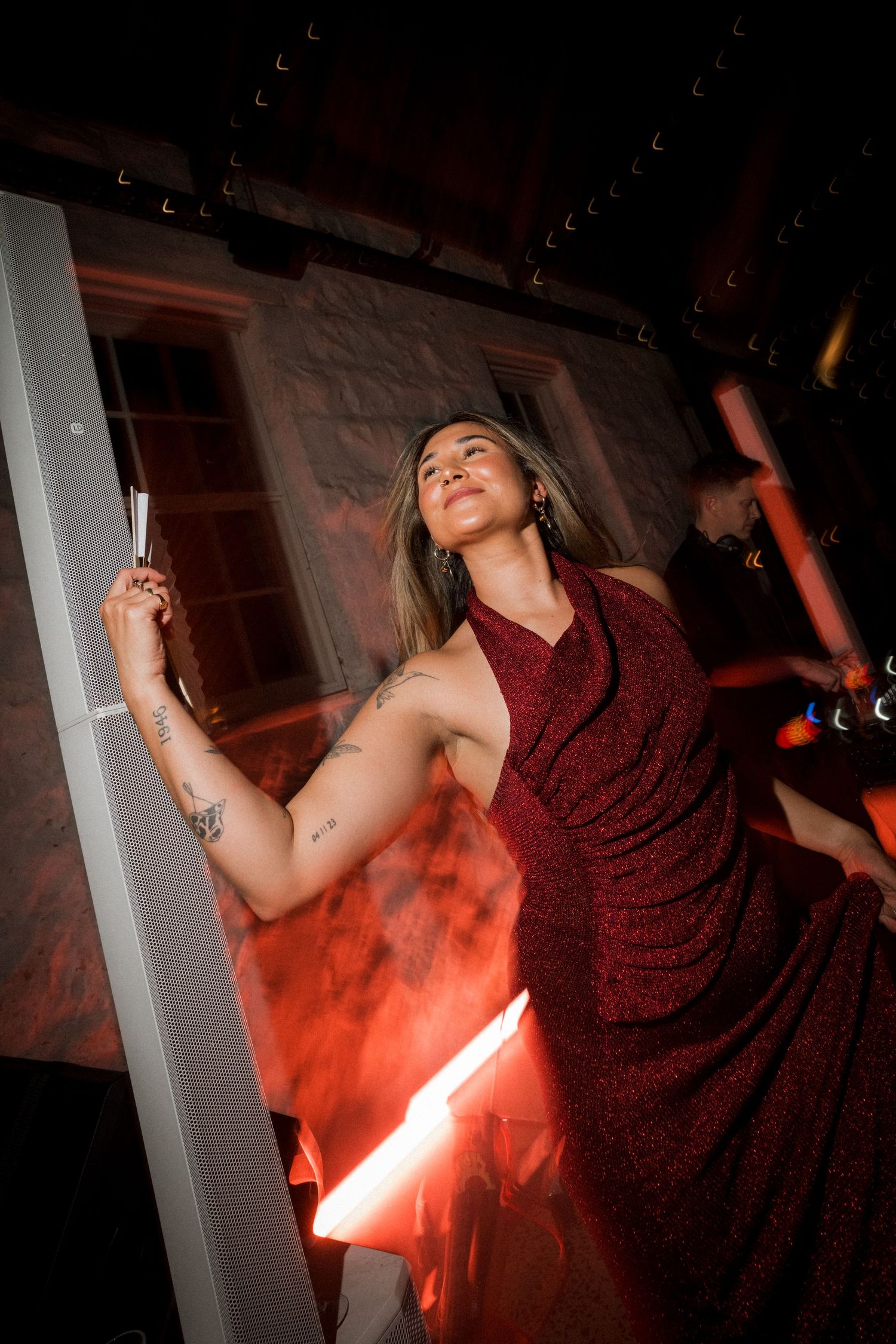 Dramatic sequence of a person in a red dress dancing with smoke effects in a dark venue.
