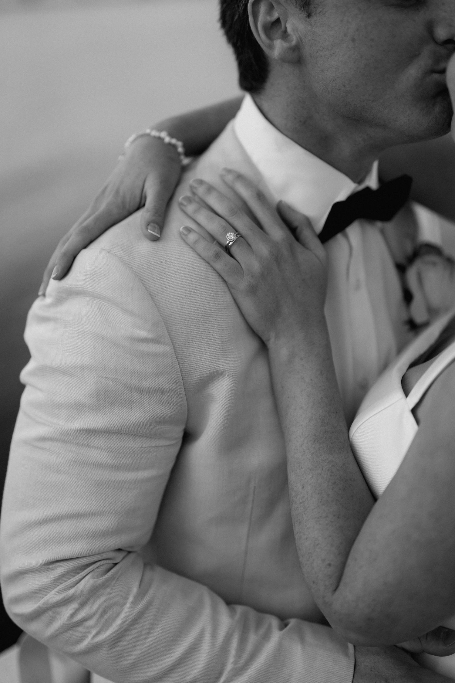 Close-up black and white shot of formal wedding attire and embracing moments.