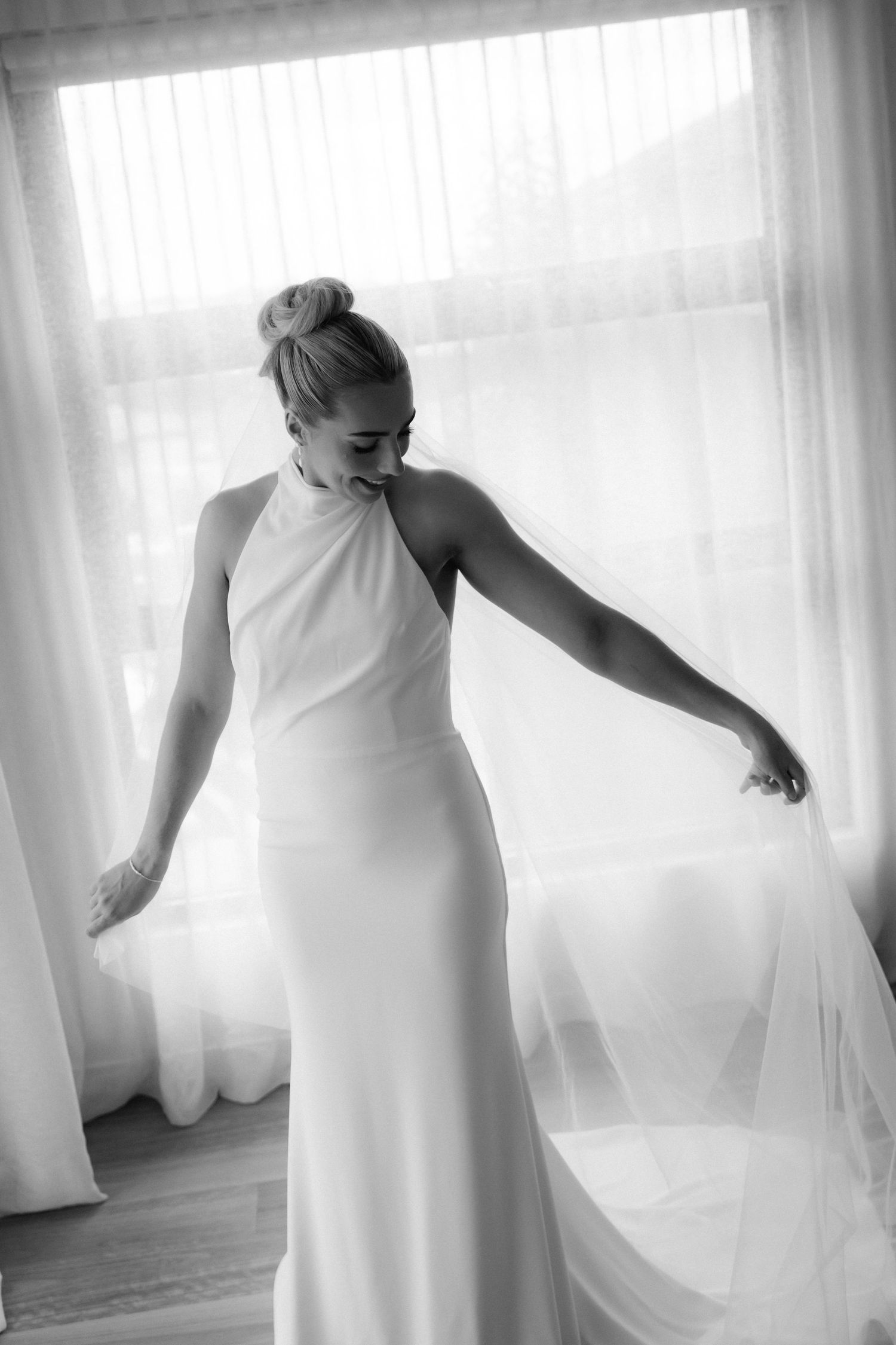 Artistic black and white series showing flowing white wedding dress details in soft window light.