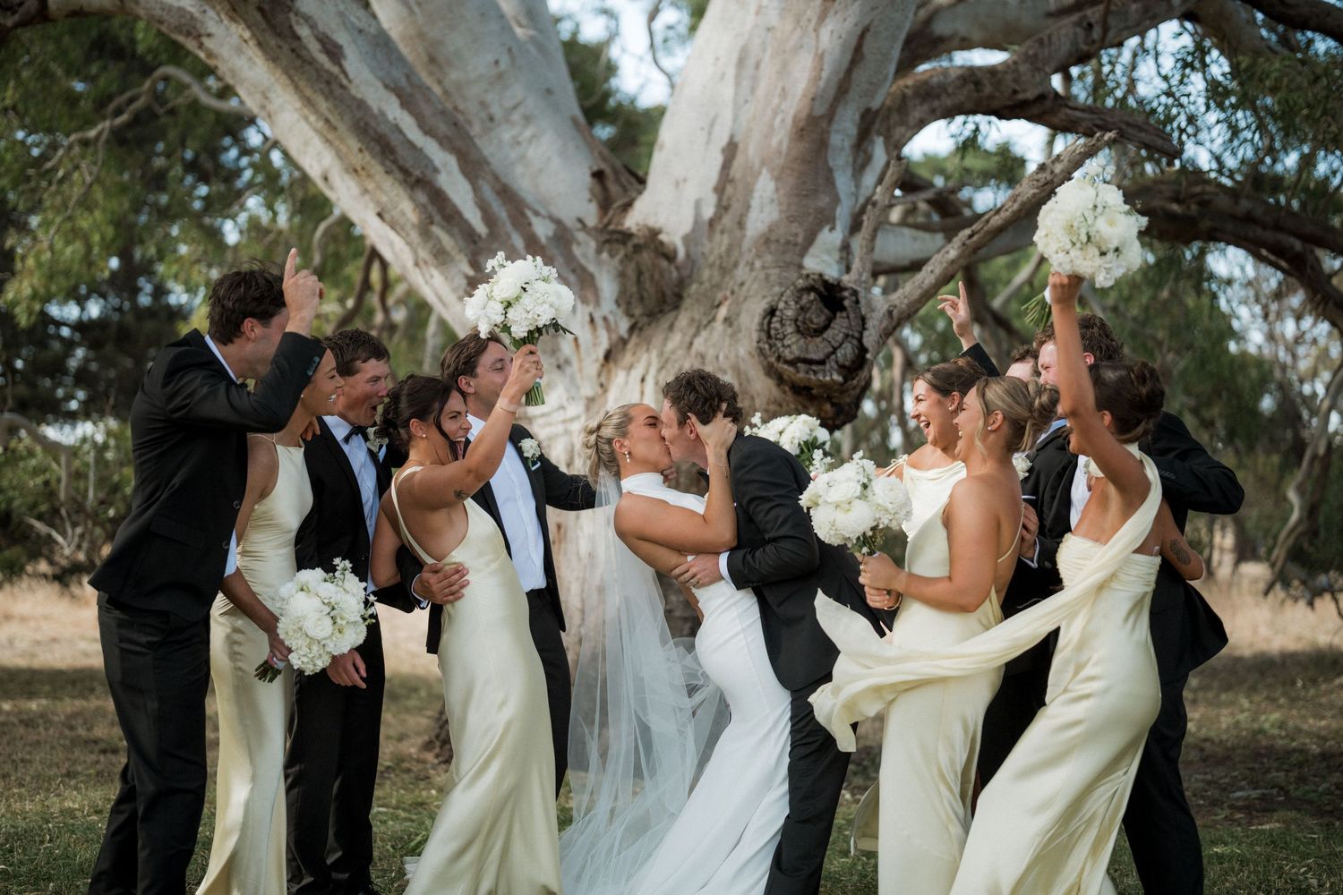 Wedding party posing together outdoors under trees in a sequence of joyful group photos.