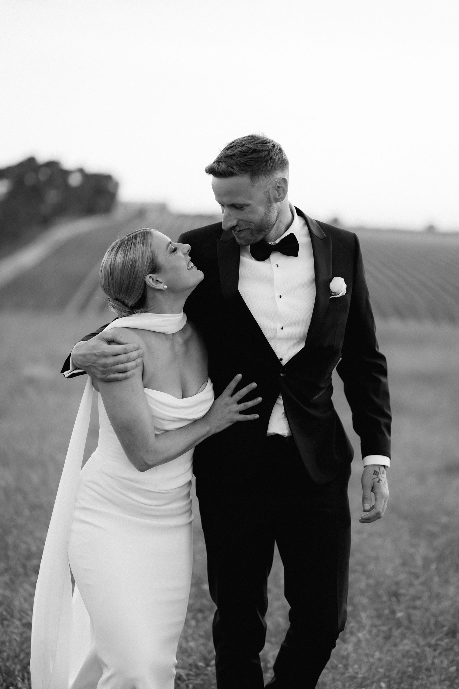Black and white romantic portraits of couple in formal attire in field setting.
