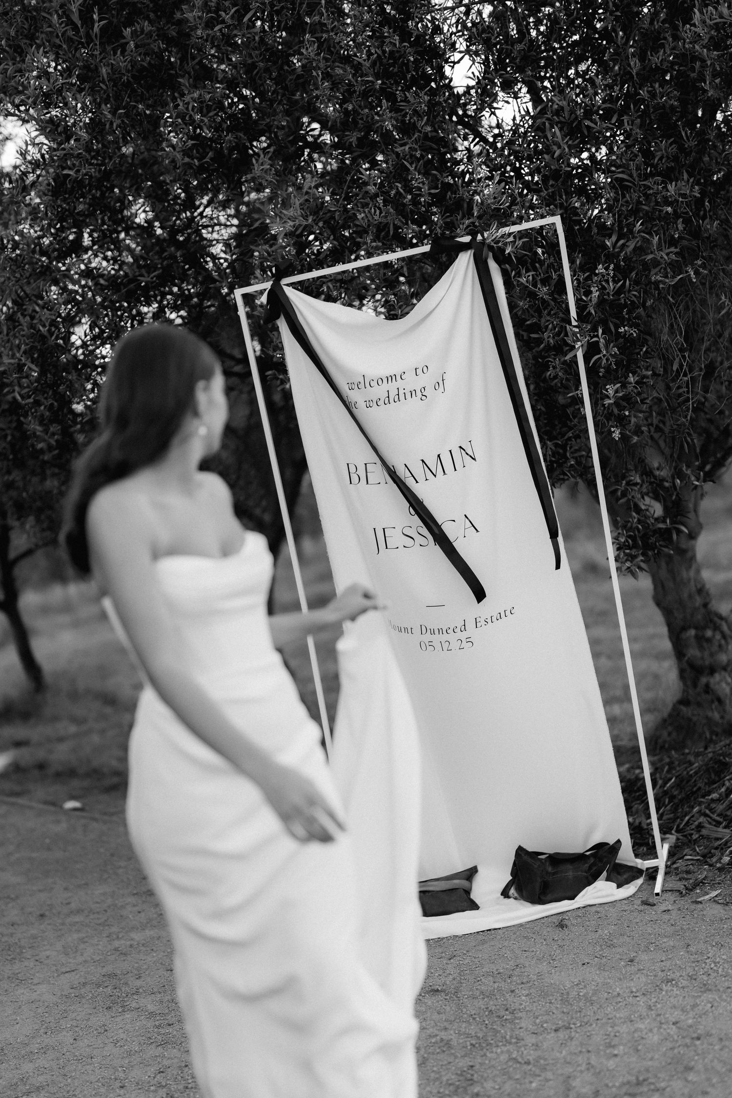 Black and white wedding welcome sign display with elegant text on fabric.