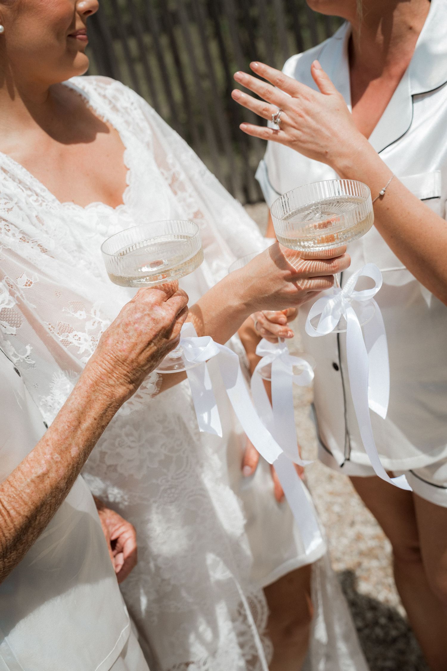 Two people in white dresses share champagne glasses during an elegant celebration.
