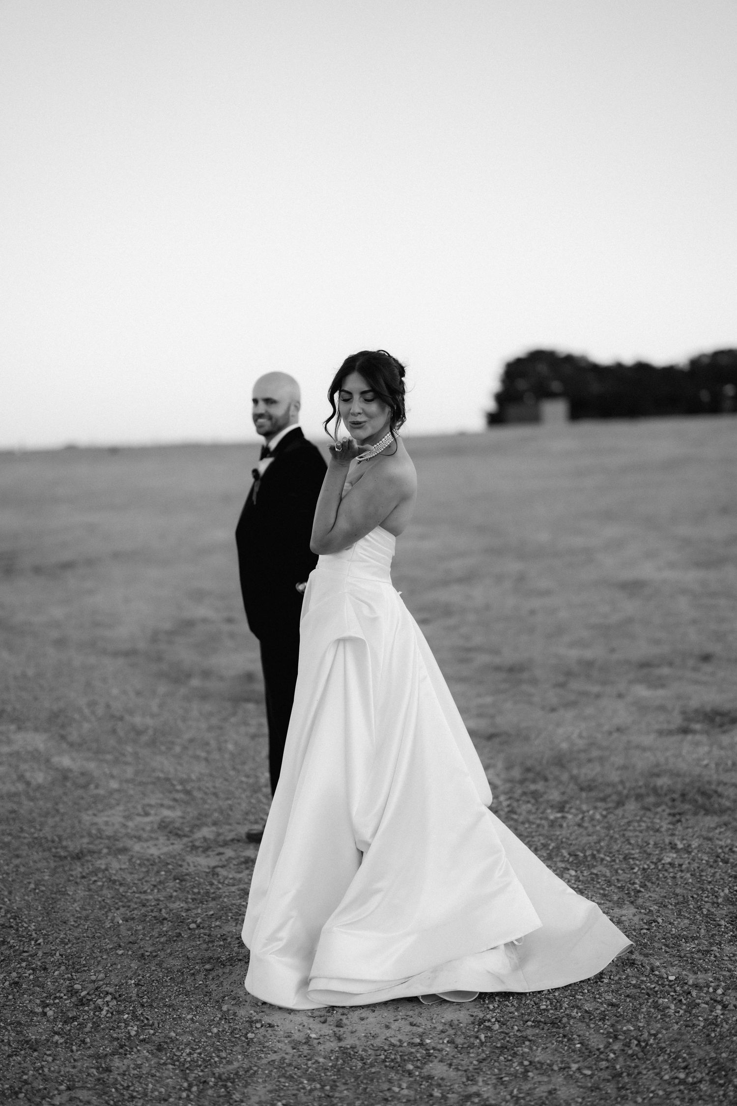 A romantic black and white photo series showing a couple dancing in an open field with a flowing white wedding dress.