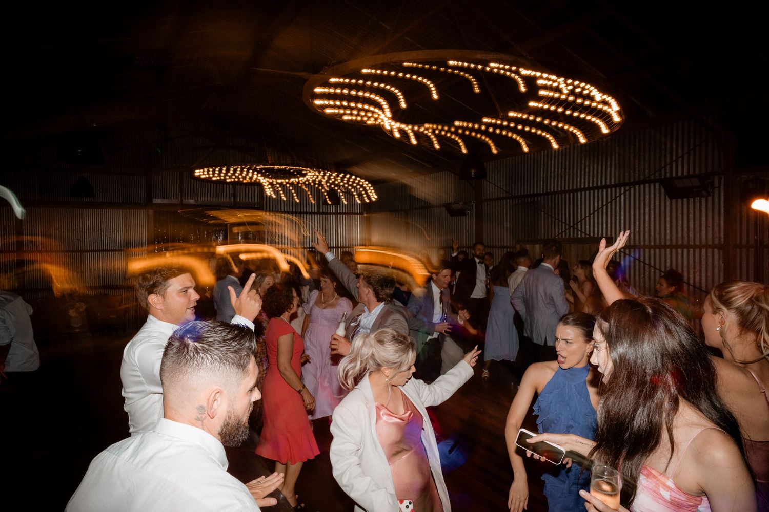 People dancing under illuminated swirling ceiling lights at a nighttime party or celebration event.