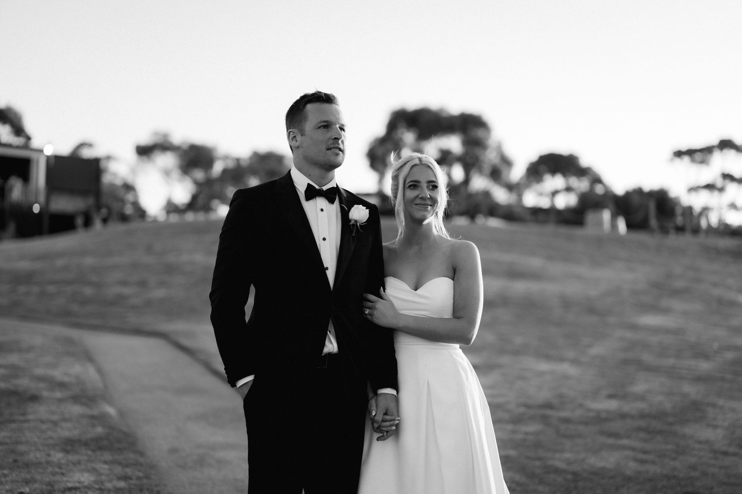 Black and white portrait of a wedding couple sharing a joyful moment outdoors.