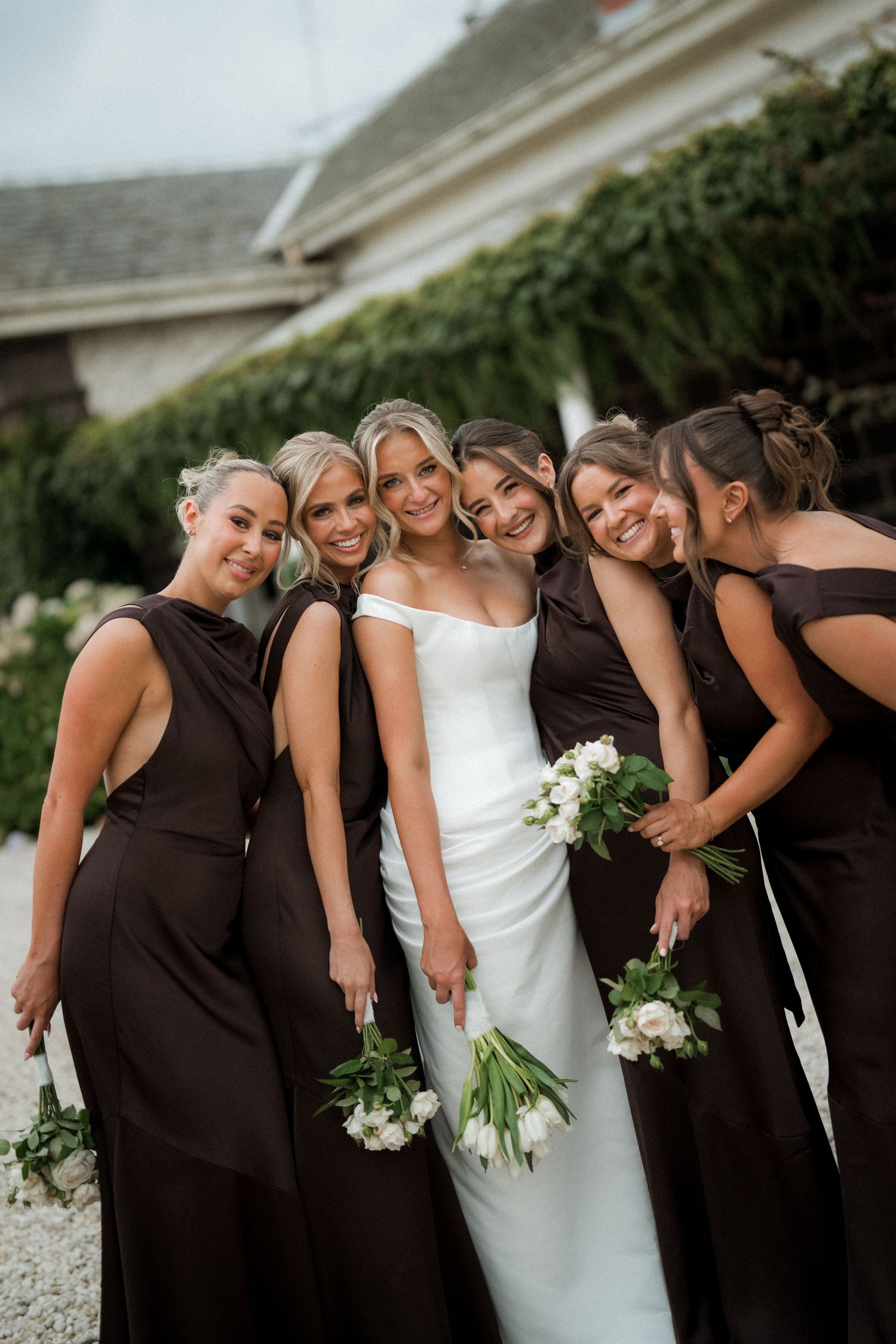 Wedding party in coordinated black and white dresses posing together outdoors.