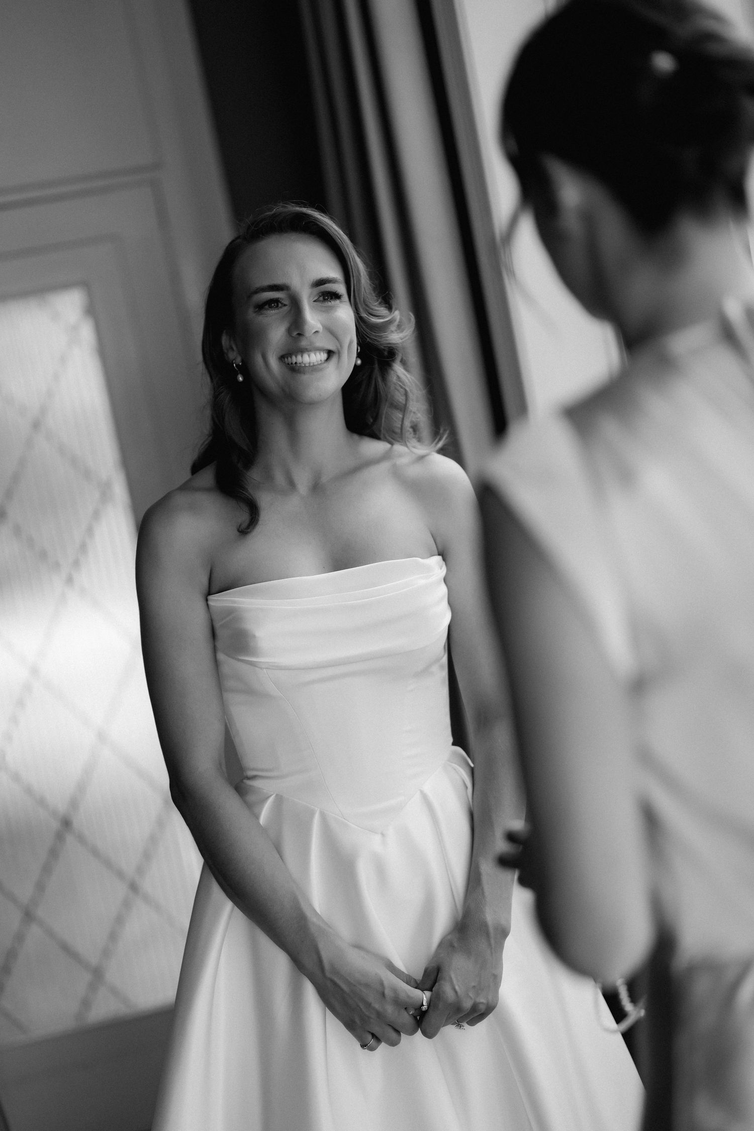 Black and white candid sequence showing a bride getting ready in an elegant white gown.