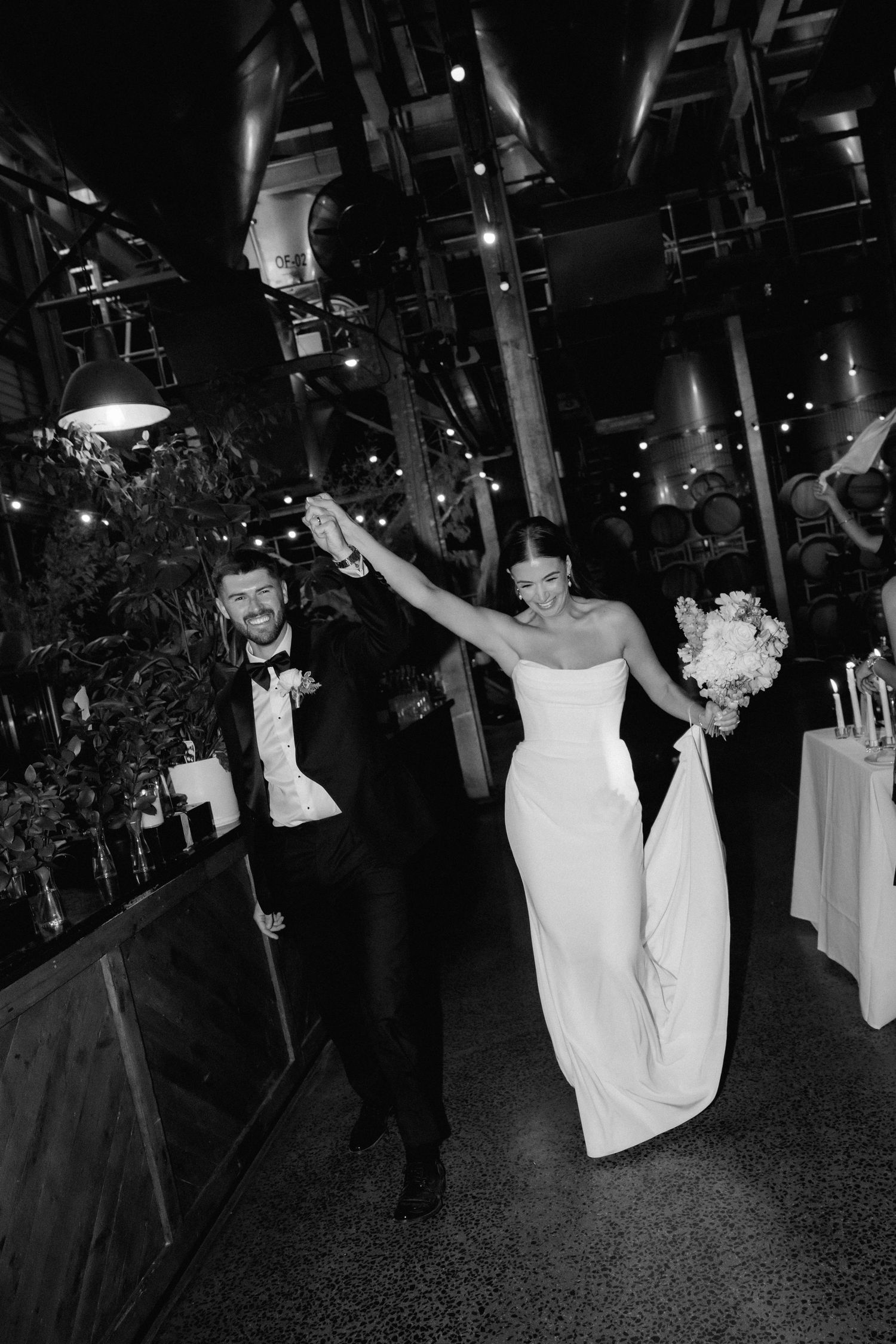 Black and white wedding photos show a couple dancing and celebrating during their reception in a dimly lit venue.