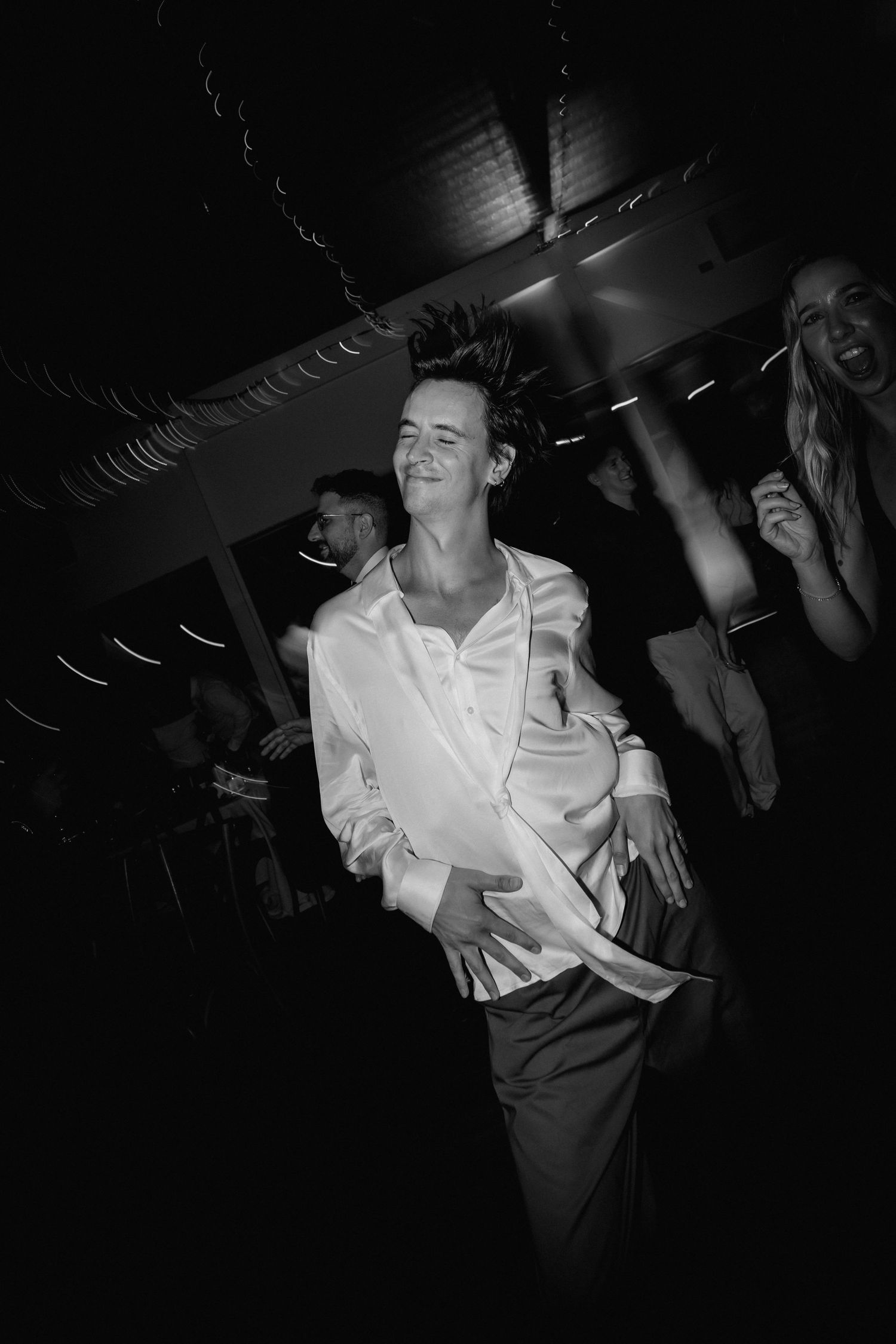 Black and white photos show people dancing and celebrating at a nightclub or party venue in dramatic lighting.
