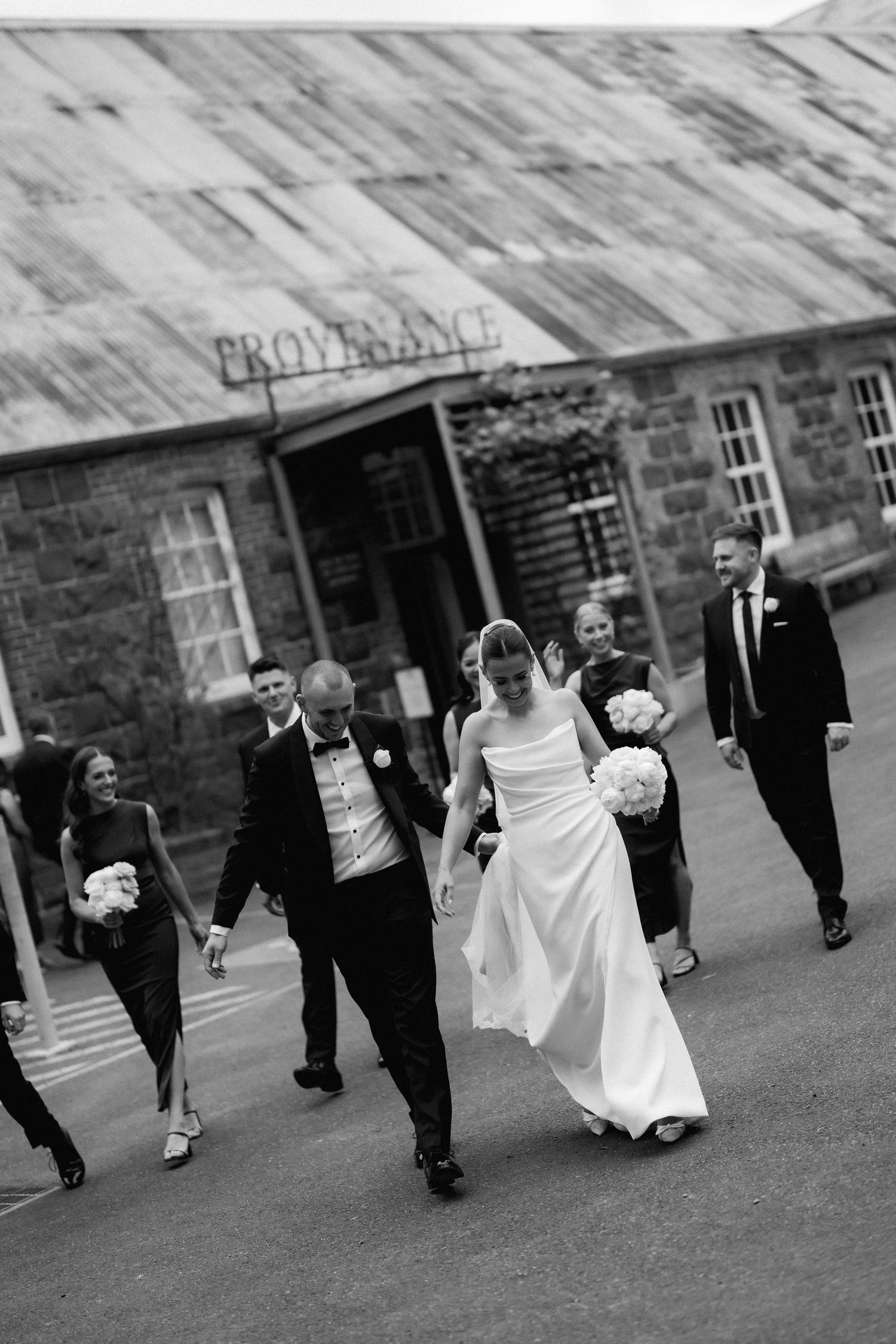 Wedding party walking together outside historic stone buildings.