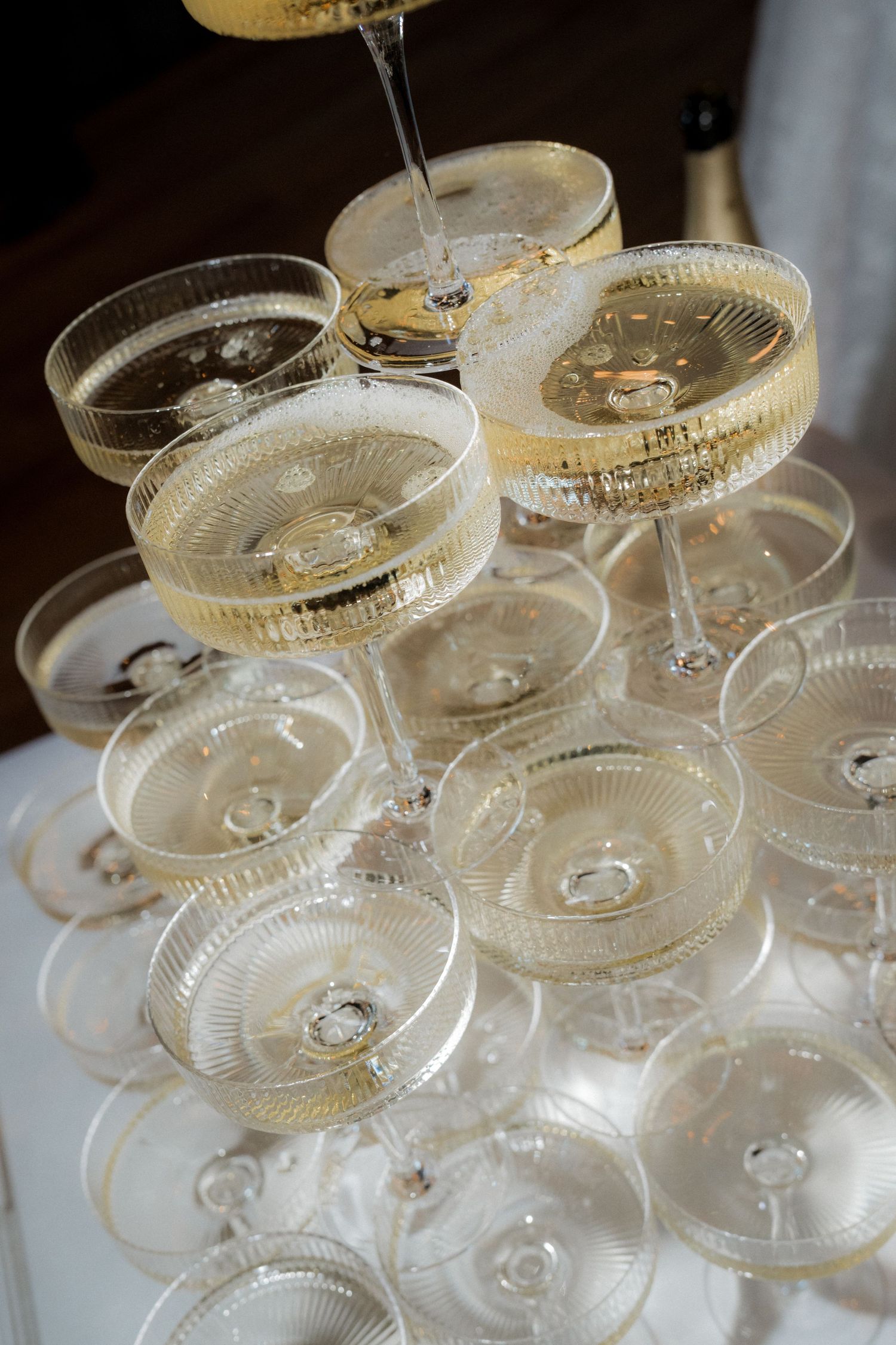 Elegant champagne tower with coupe glasses filled with sparkling wine at wedding reception.