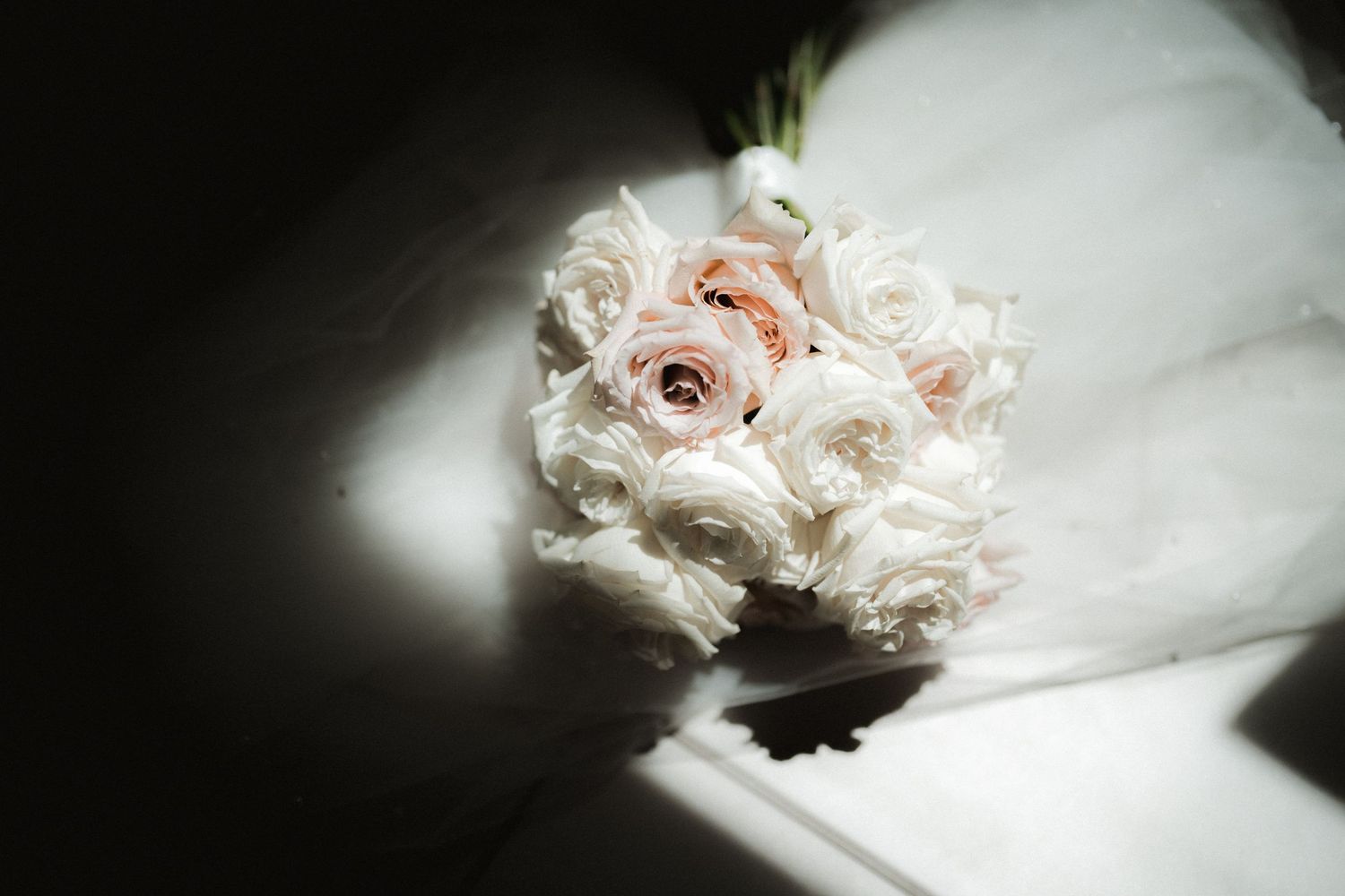 A soft pink rose bouquet arranged with white tulle fabric in a dreamy, ethereal composition.