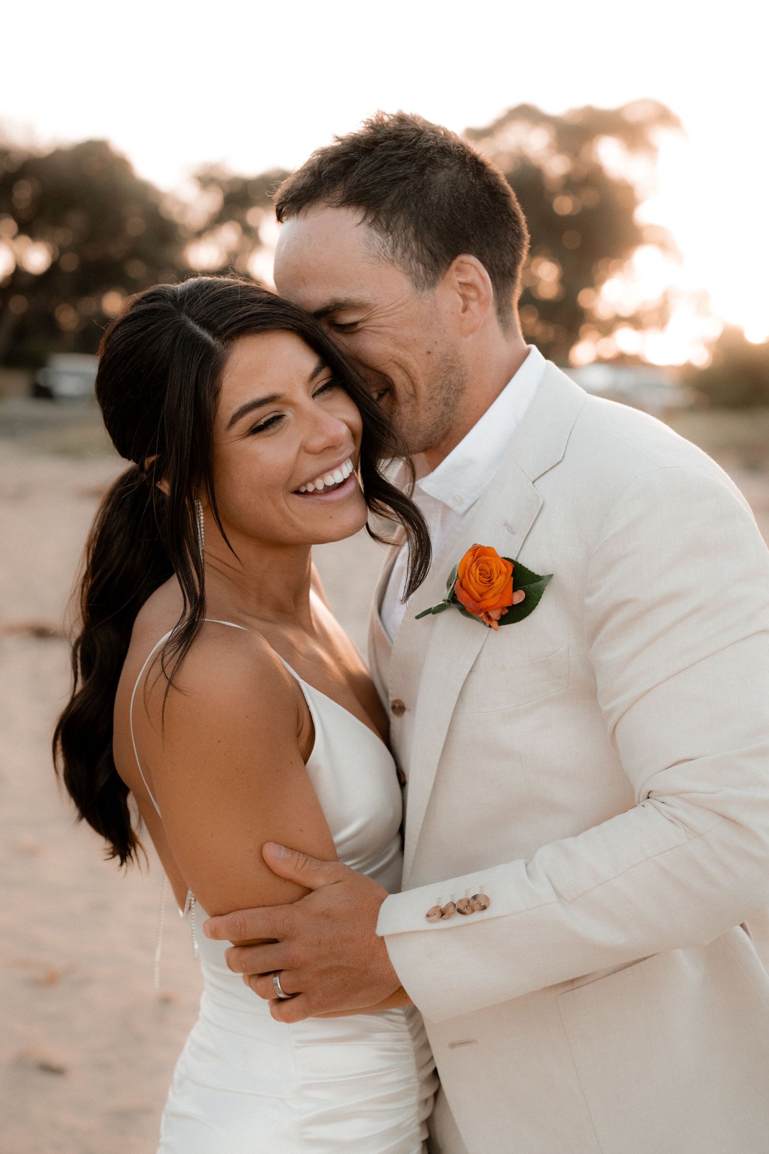 Romantic sunset beach wedding portrait in white attire.