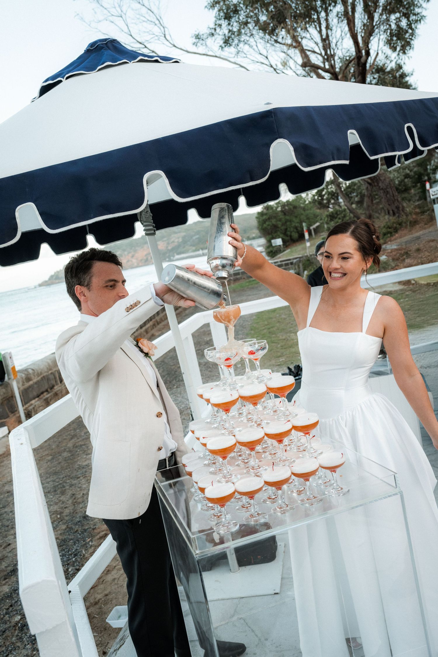 Wedding reception setup with champagne glasses and white decor under a navy blue tent canopy.