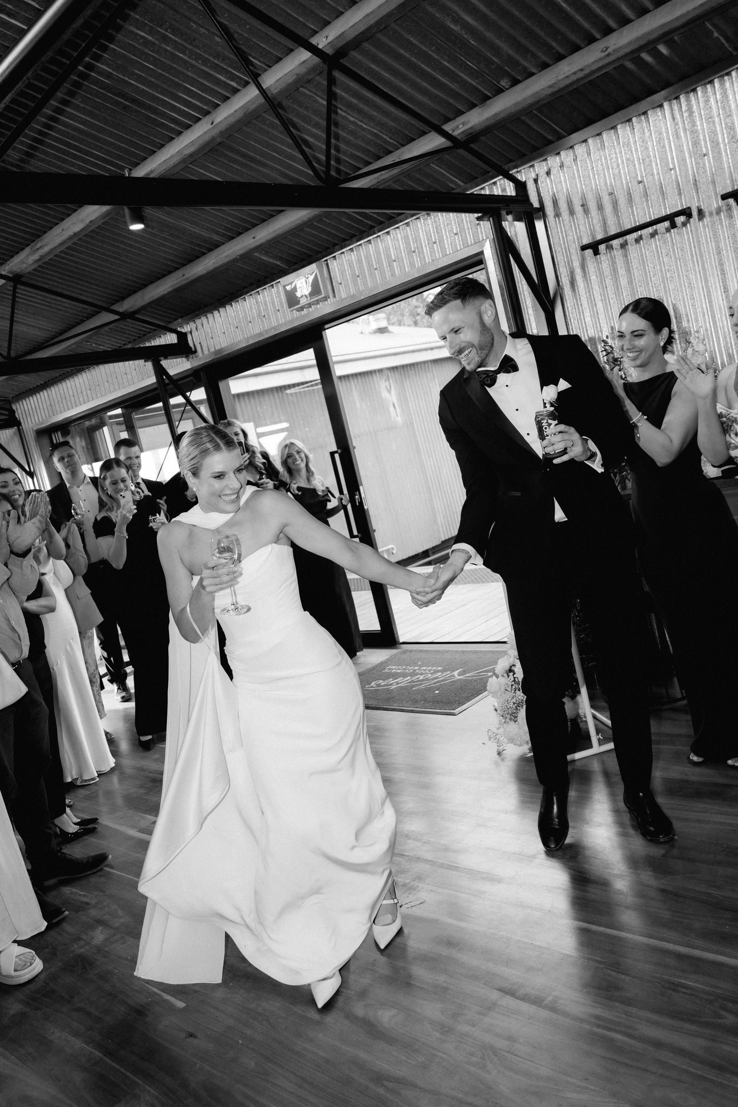 Wedding couple performs first dance in reception venue with dramatic lighting.