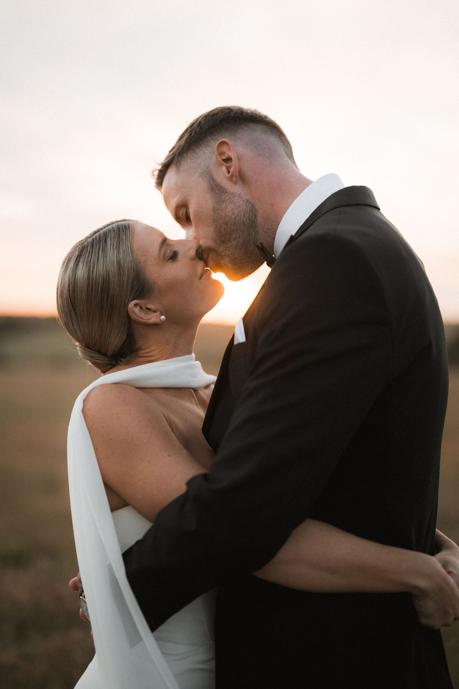 Romantic sunset wedding portraits with couple in elegant attire.