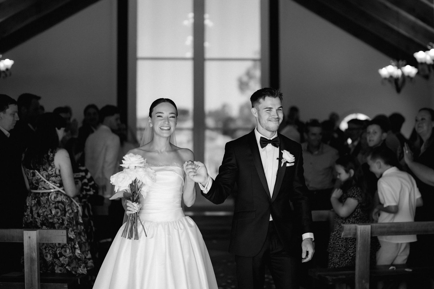 Wedding party walking outdoors during an evening reception in black and white.