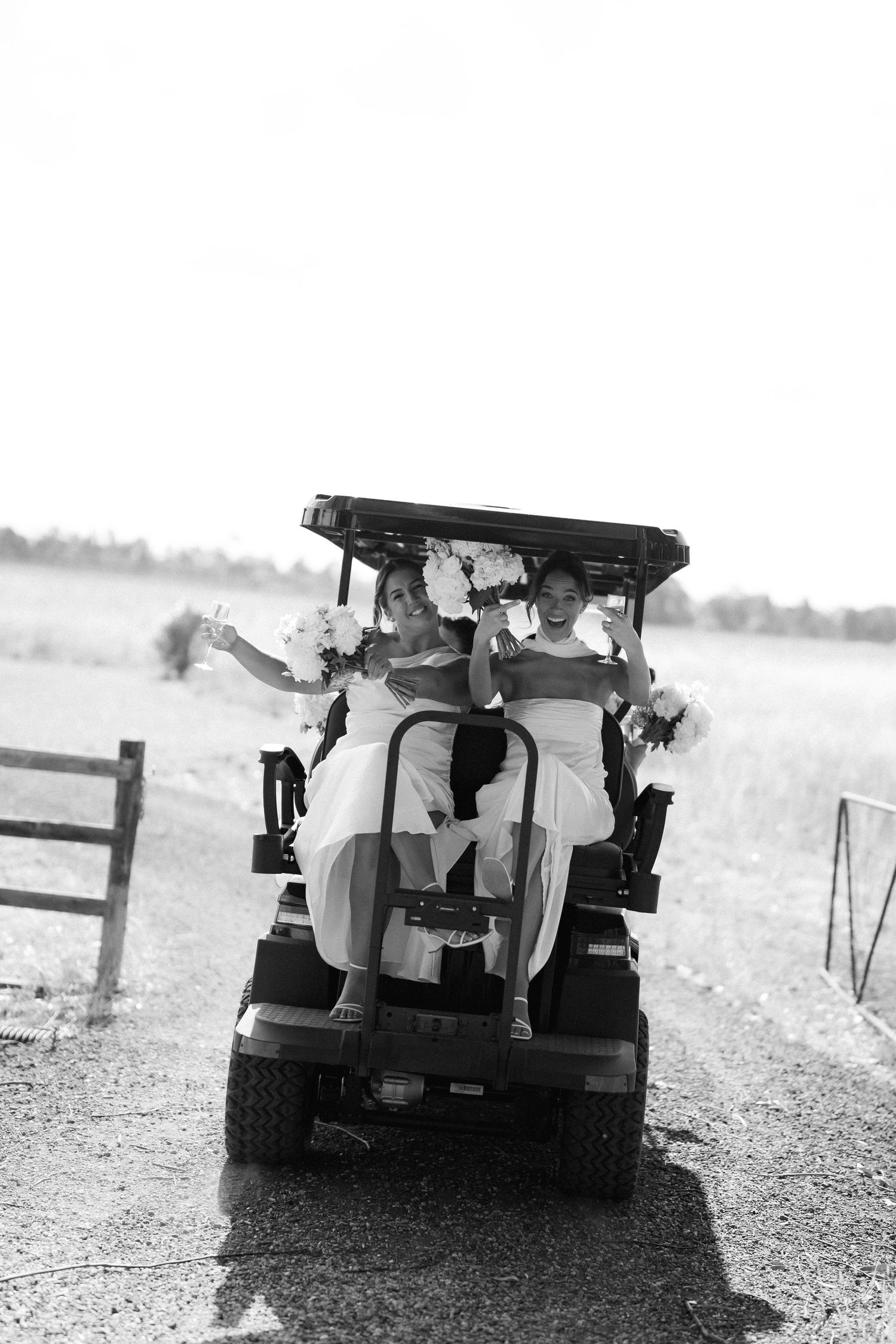 Wedding party riding in a golf cart captured in black and white photography.
