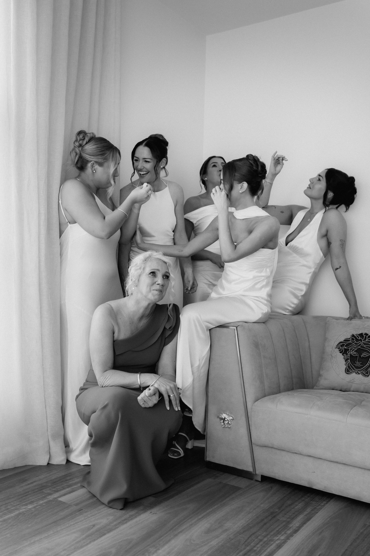 Wedding party relaxing and laughing together on a grey couch.