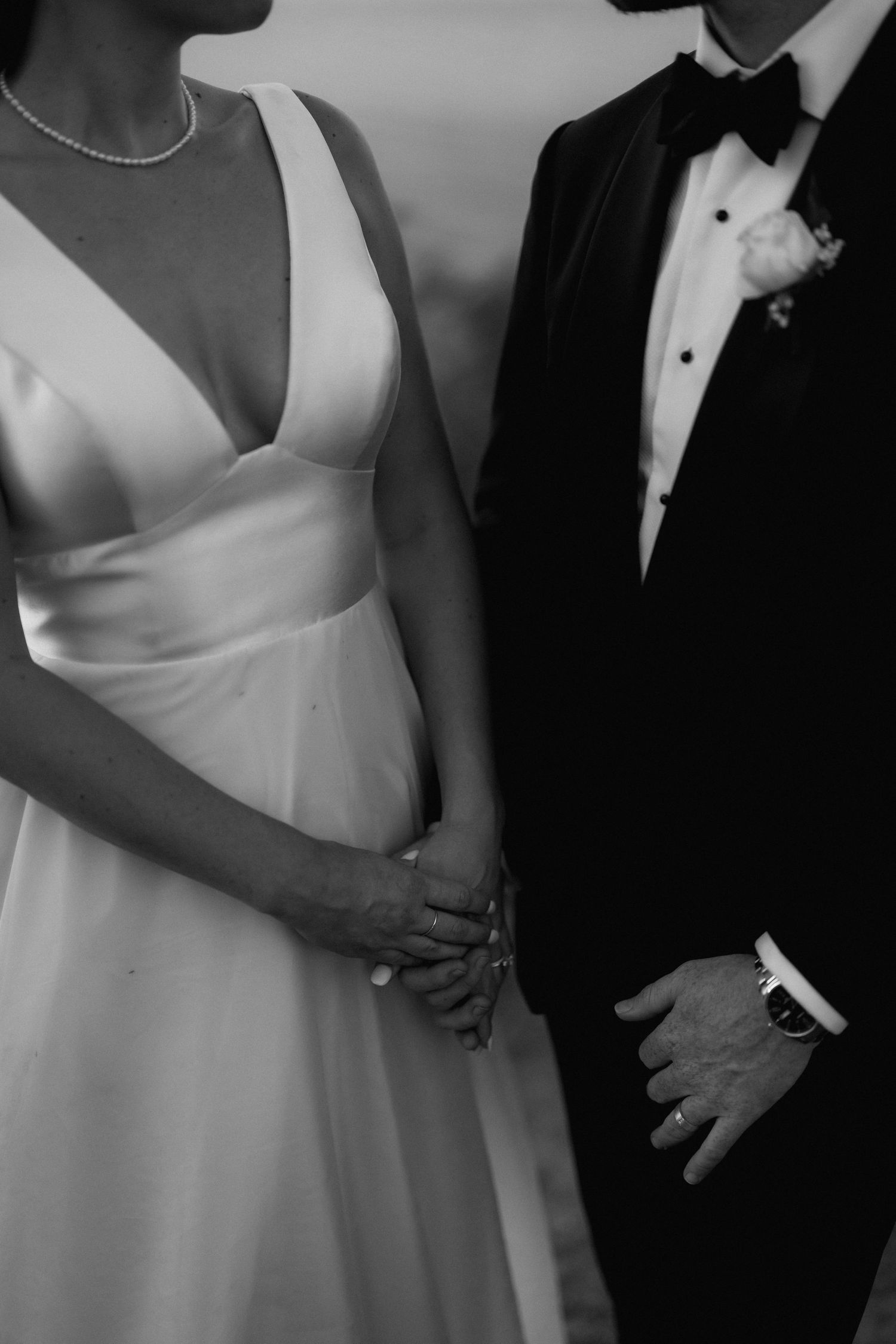 Close-up details of formal wedding attire showing white dresses and black tuxedos.