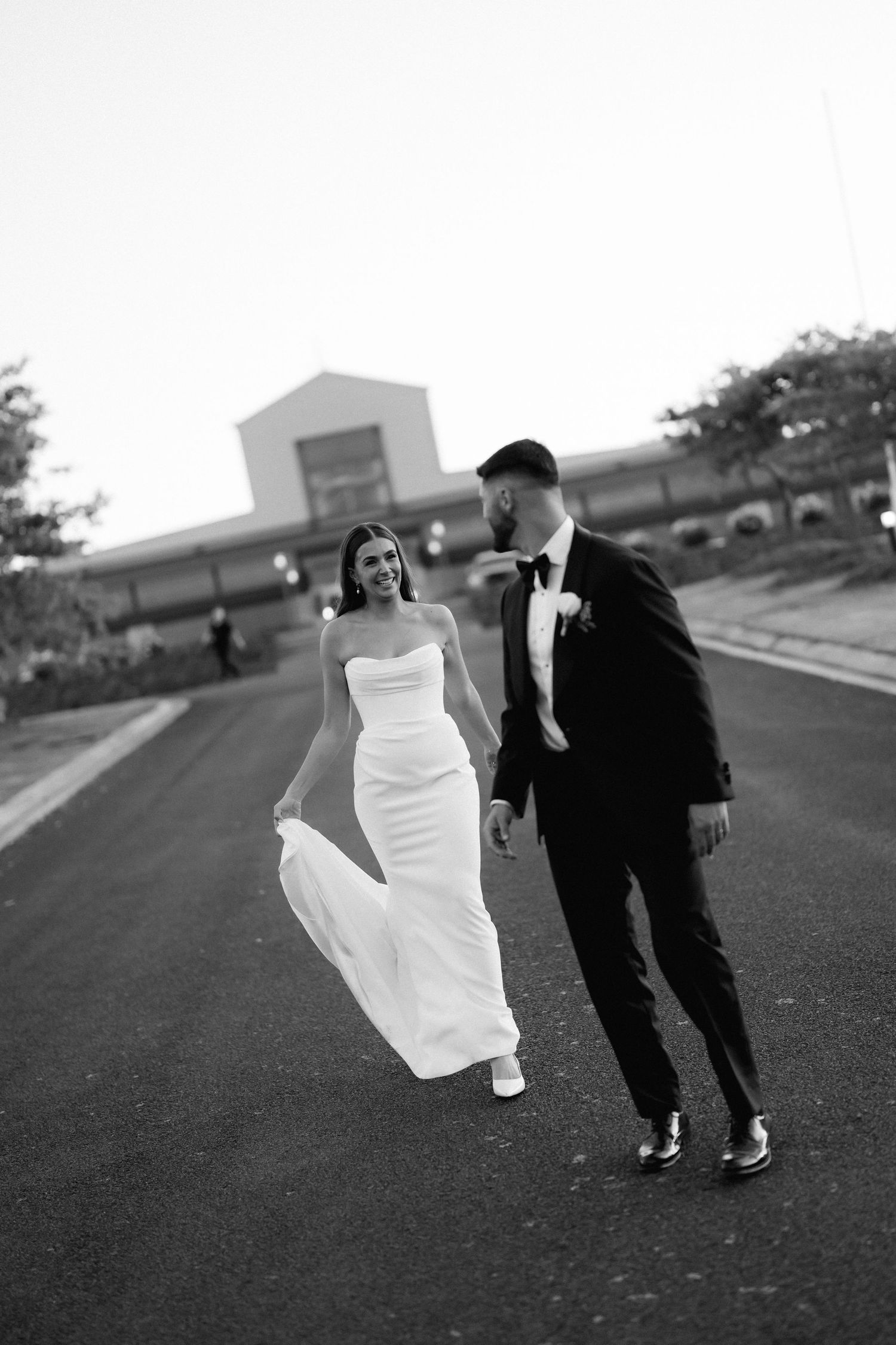 Black and white wedding photo series showing couple running playfully on an outdoor path in formal attire.