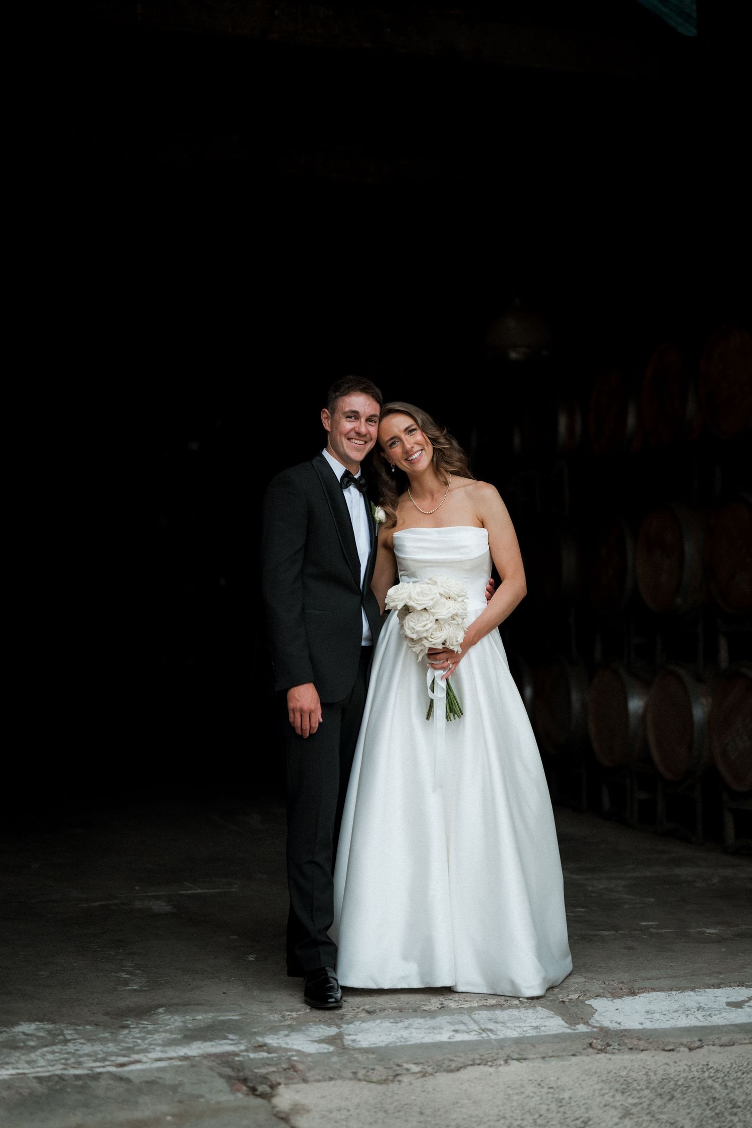 A wedding couple shares intimate moments in a dimly lit rustic venue with stone walls.