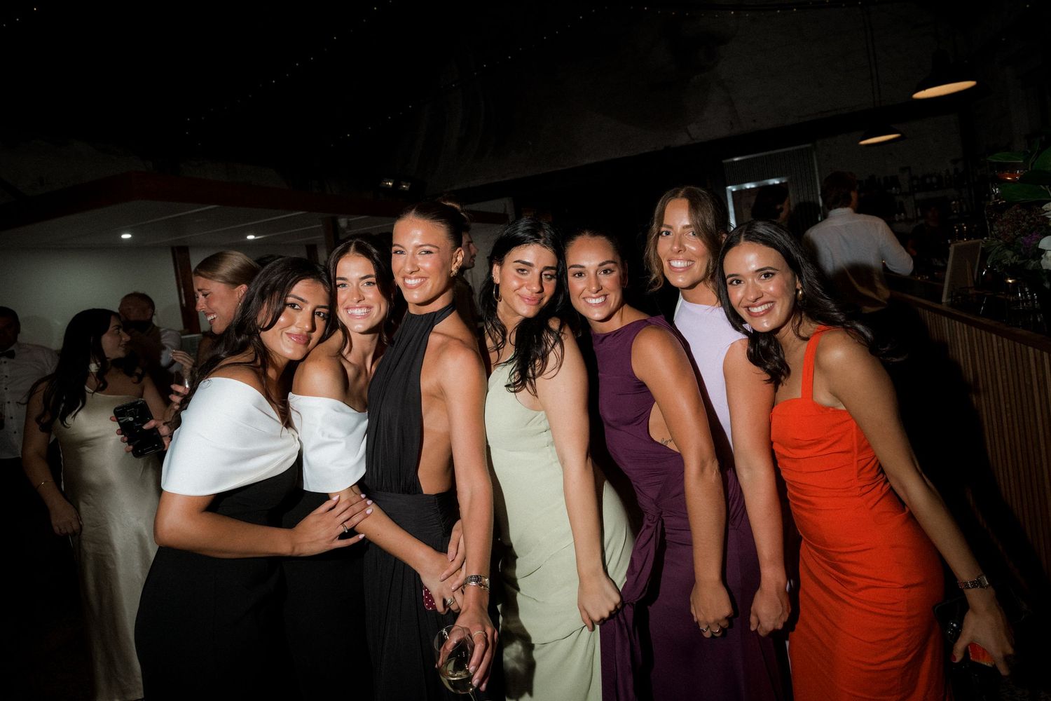 Group of people dancing and celebrating at a dimly lit party venue with festive atmosphere.